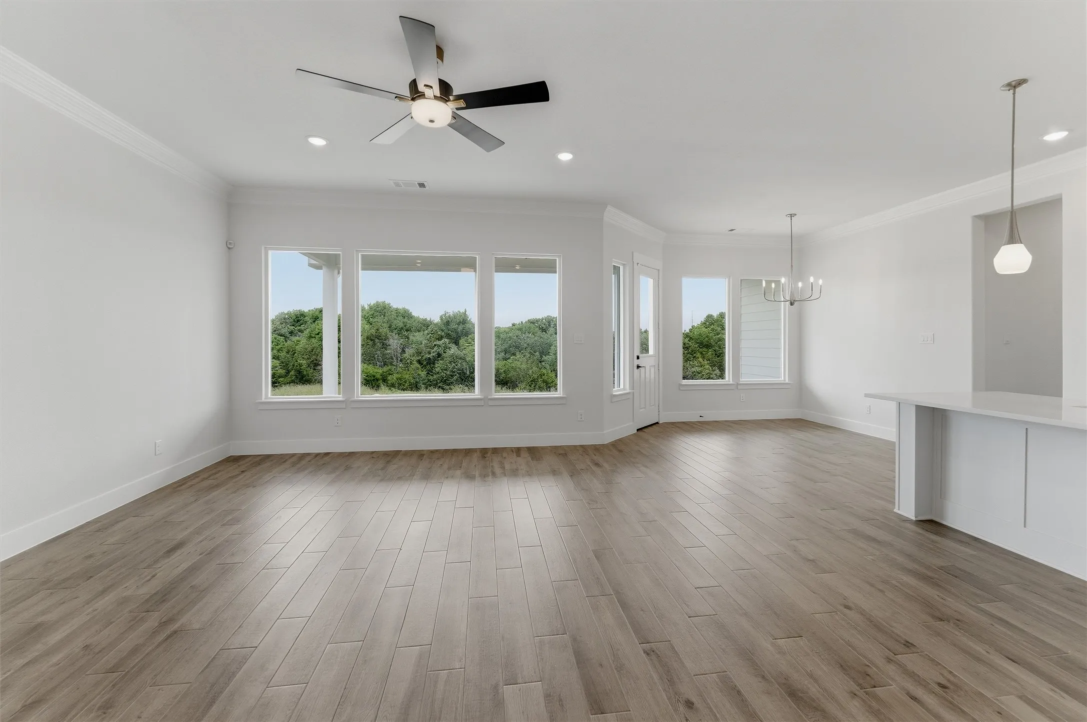 Spacious interior showcasing wood-finish flooring, recessed lighting, and crown molding