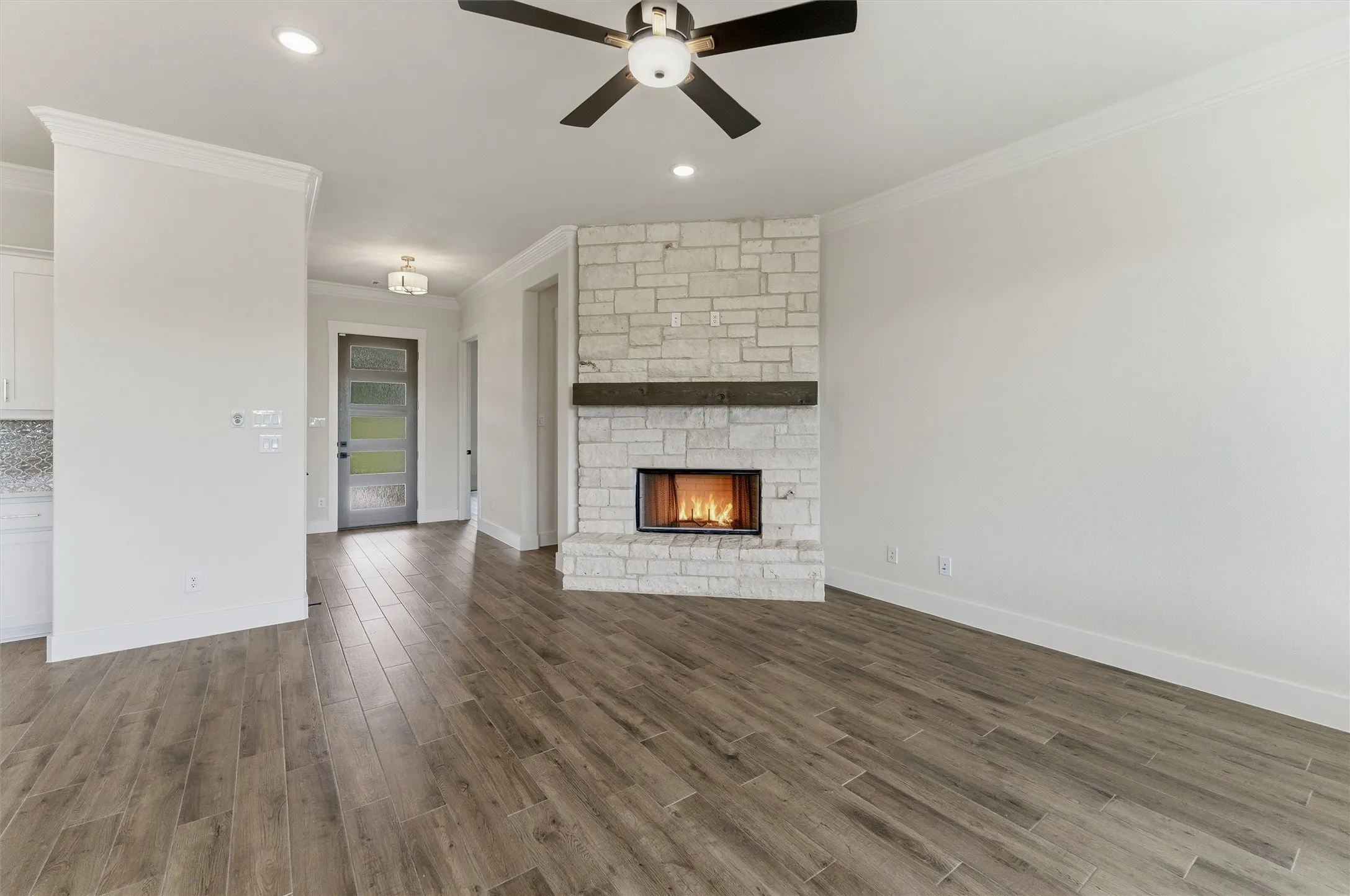 Living space featuring a stone-clad fireplace with a wood mantel, wood-finish flooring, and recessed lighting
