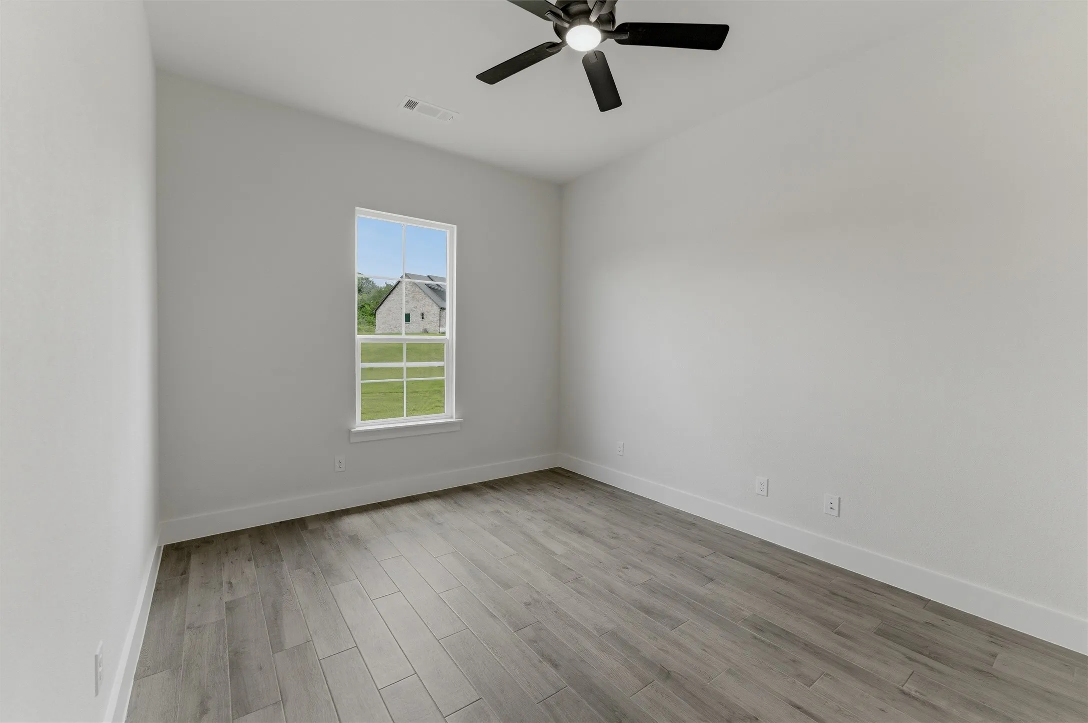 Interior space featuring wood-finish flooring, white baseboards, a white window frame, and a ceiling fan with integrated lighting
