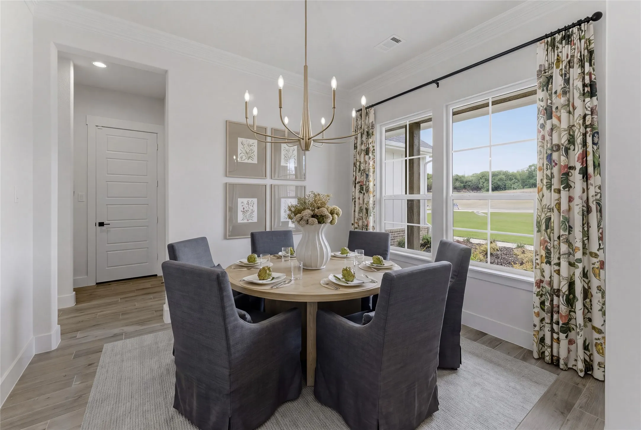 Spacious dining area featuring a contemporary chandelier, large windows, crown molding, and wood-finish flooring