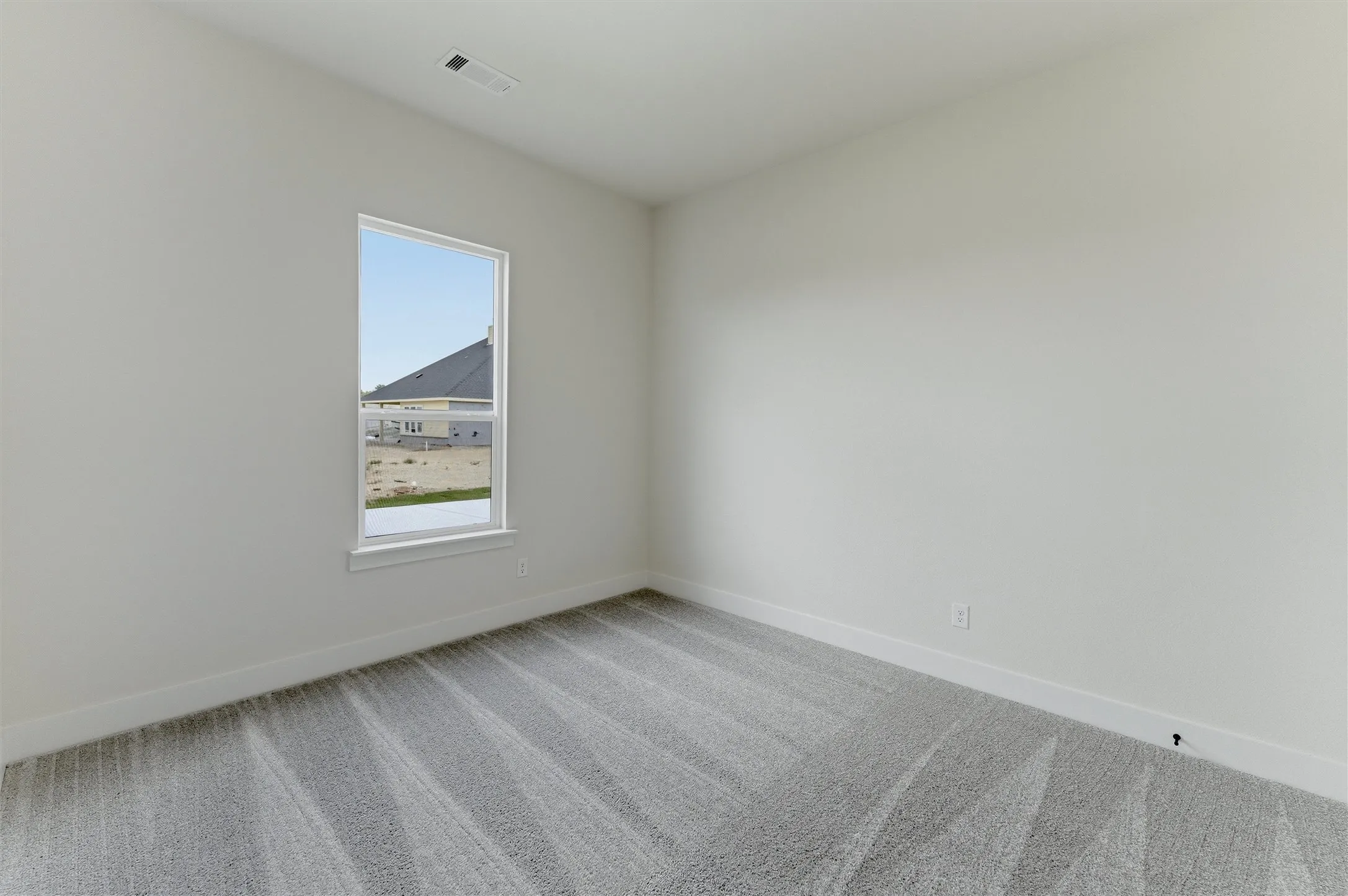 Room featuring light gray walls, white trim, a single window with white framing, and gray patterned carpet