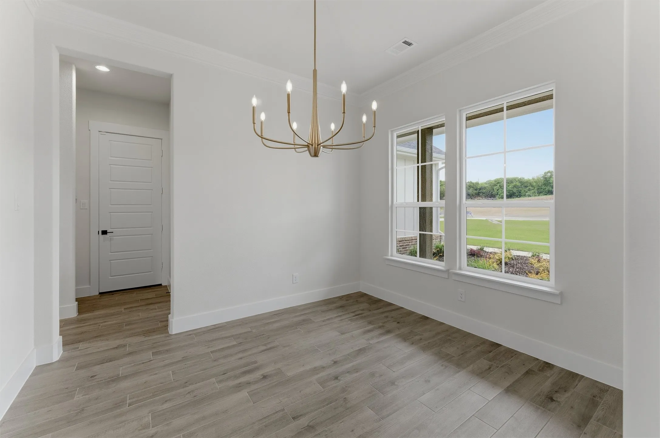 Spacious room featuring wood-finish flooring, a modern chandelier, and dual windows