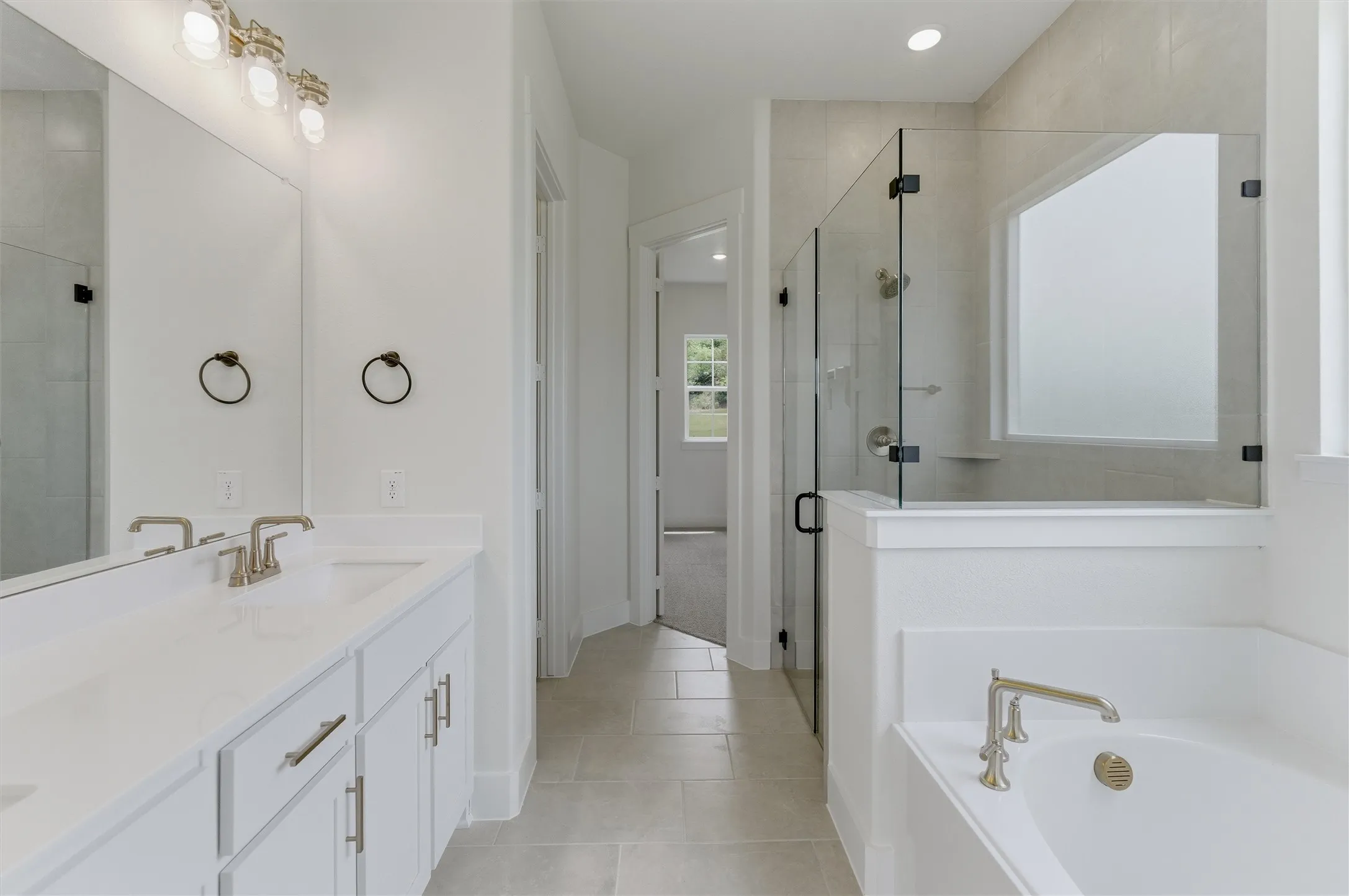 Contemporary bathroom featuring dual vanities with white cabinetry, light-toned countertops, and brushed nickel fixtures