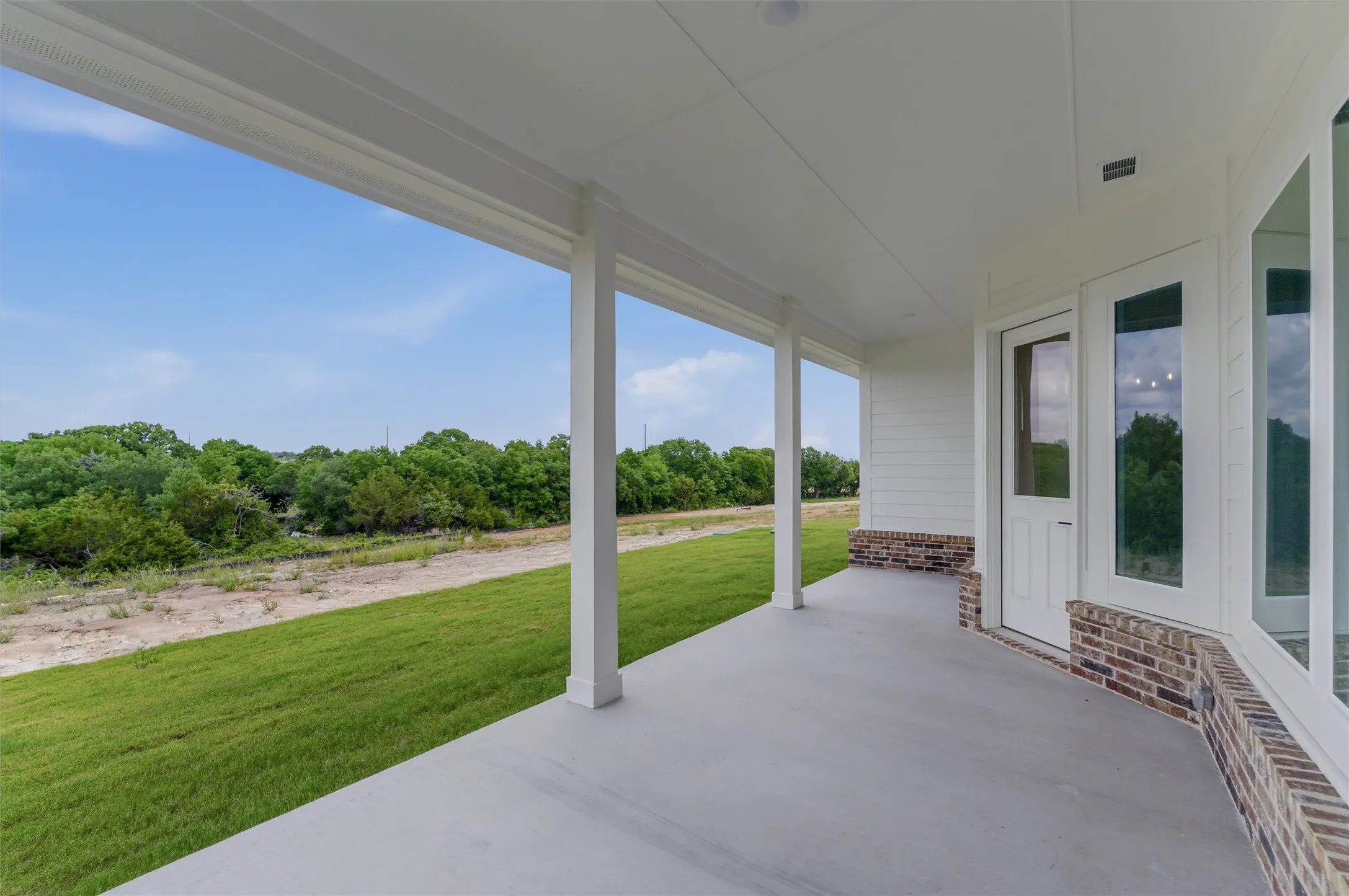 Expansive covered patio featuring a concrete surface and white support columns