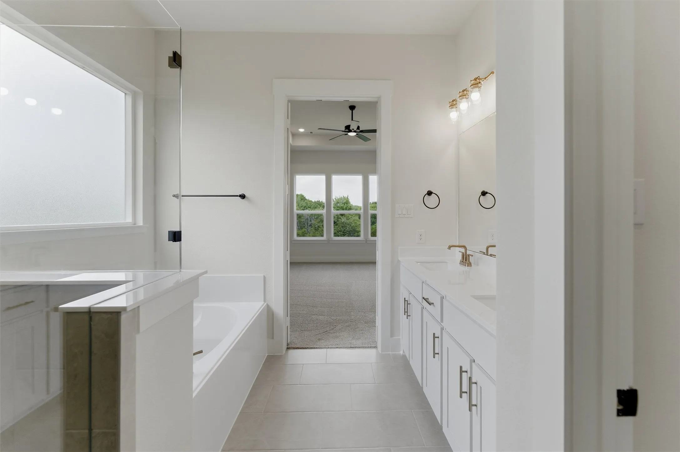 Contemporary bathroom featuring dual vanities with white cabinetry and light-toned countertops, a built-in tub, and a separate shower with a clear glass enclosure