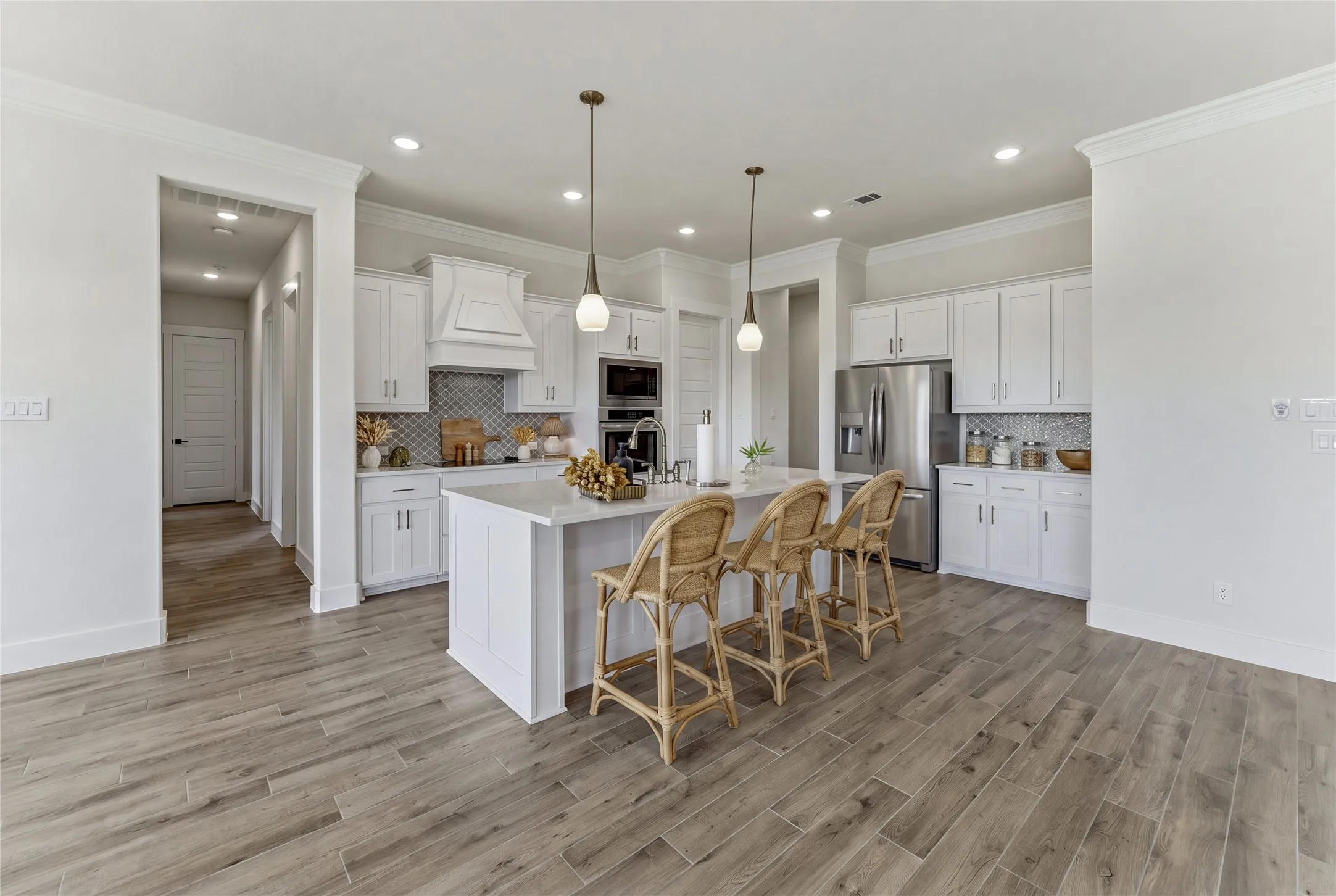 Gourmet kitchen featuring a center island, white cabinetry, integrated stainless steel appliances, a tiled backsplash, and wood-finish flooring