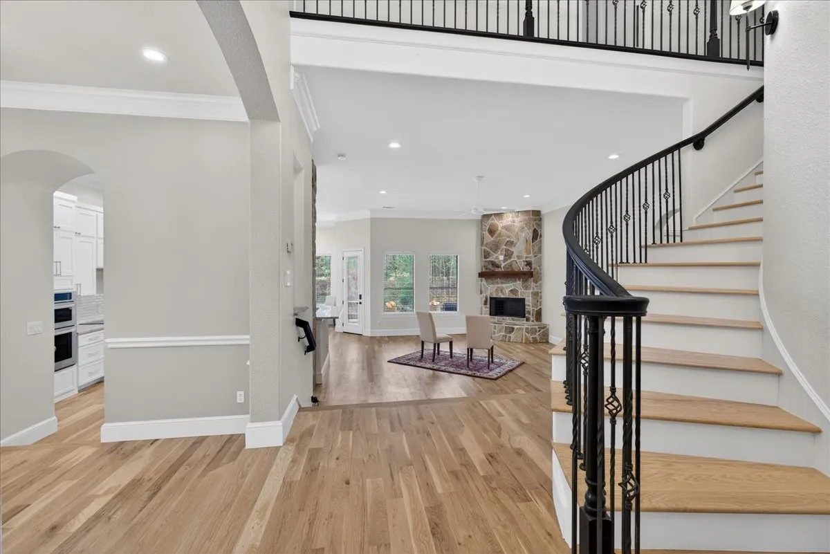 Foyer entrance with arched walkways, light wood-style floors, crown molding, recessed lighting, and a fireplace