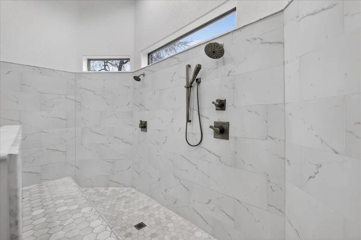 Bathroom featuring tiled shower and healthy amount of natural light