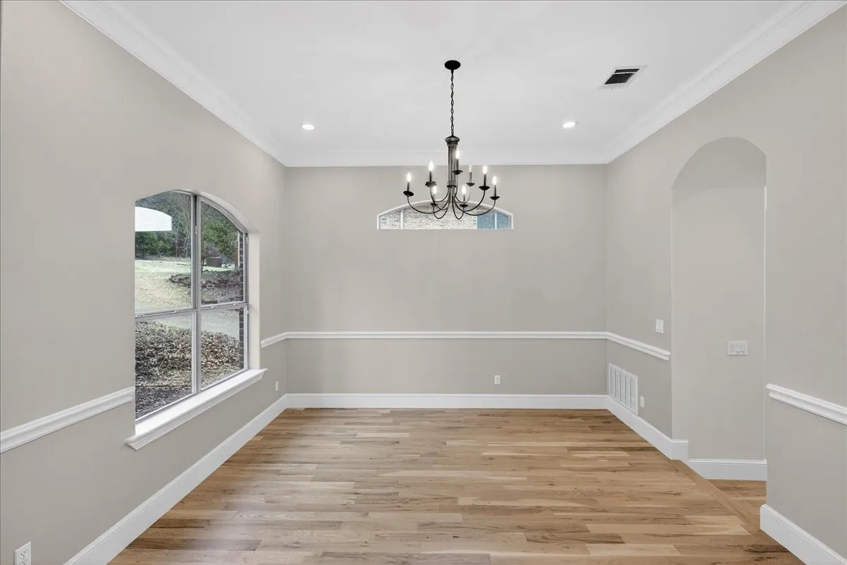 Unfurnished dining area featuring light wood finished floors, suspended lighting, and ornamental molding