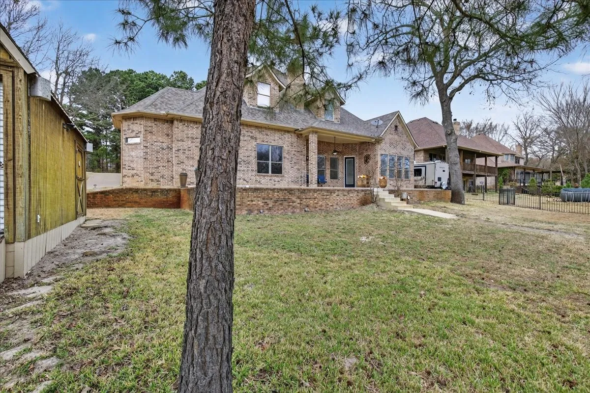 Back of house featuring brick siding, a patio, and a shingled roof