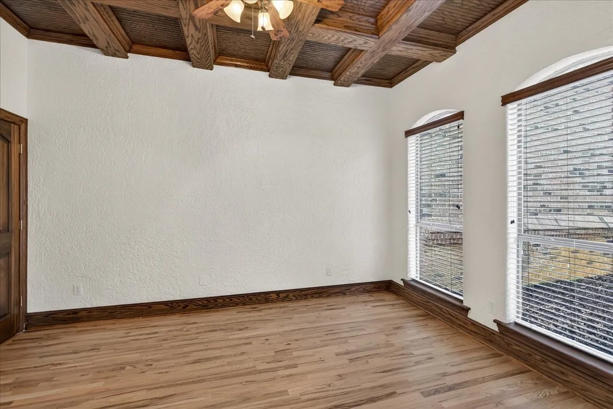 Empty room with wooden ceiling, a ceiling fan, coffered ceiling, wood finished floors, and a textured wall
