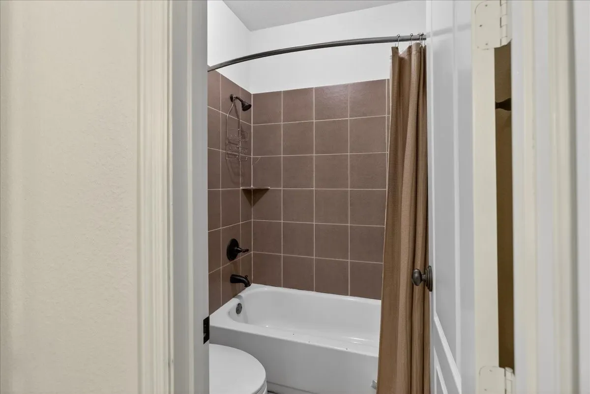 Bathroom with shower / bath combination with curtain and toilet