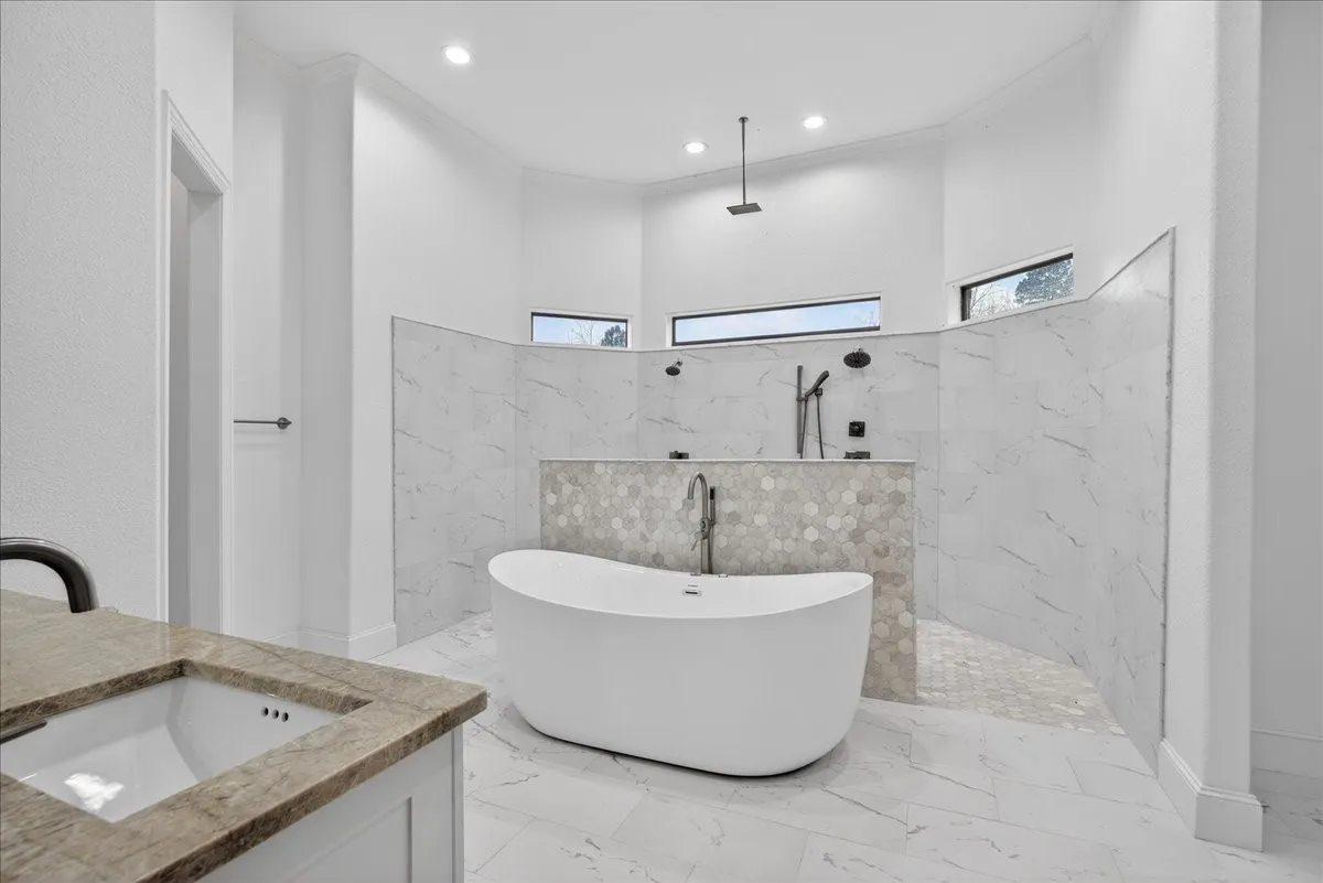 Bathroom featuring a marble finish shower, a freestanding bath, vanity, light marble finish flooring, and recessed lighting