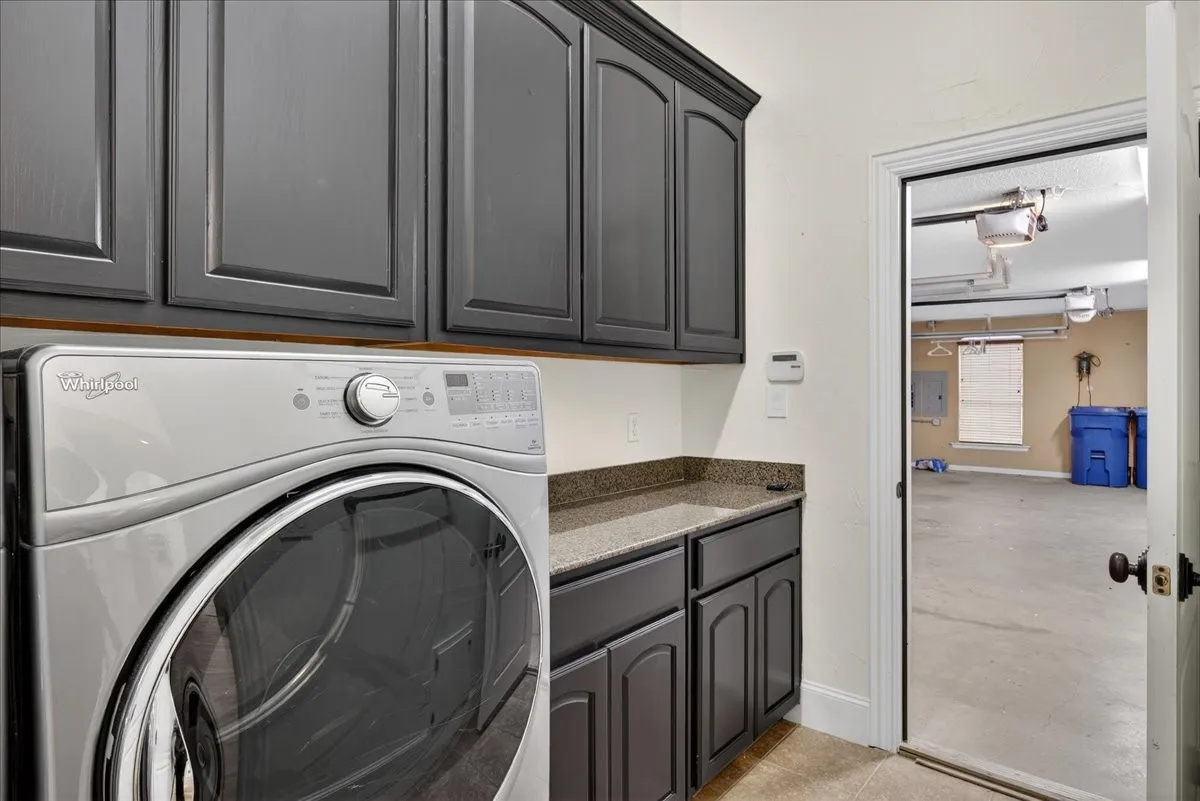 Laundry room featuring washer / clothes dryer, cabinet space, and electric panel
