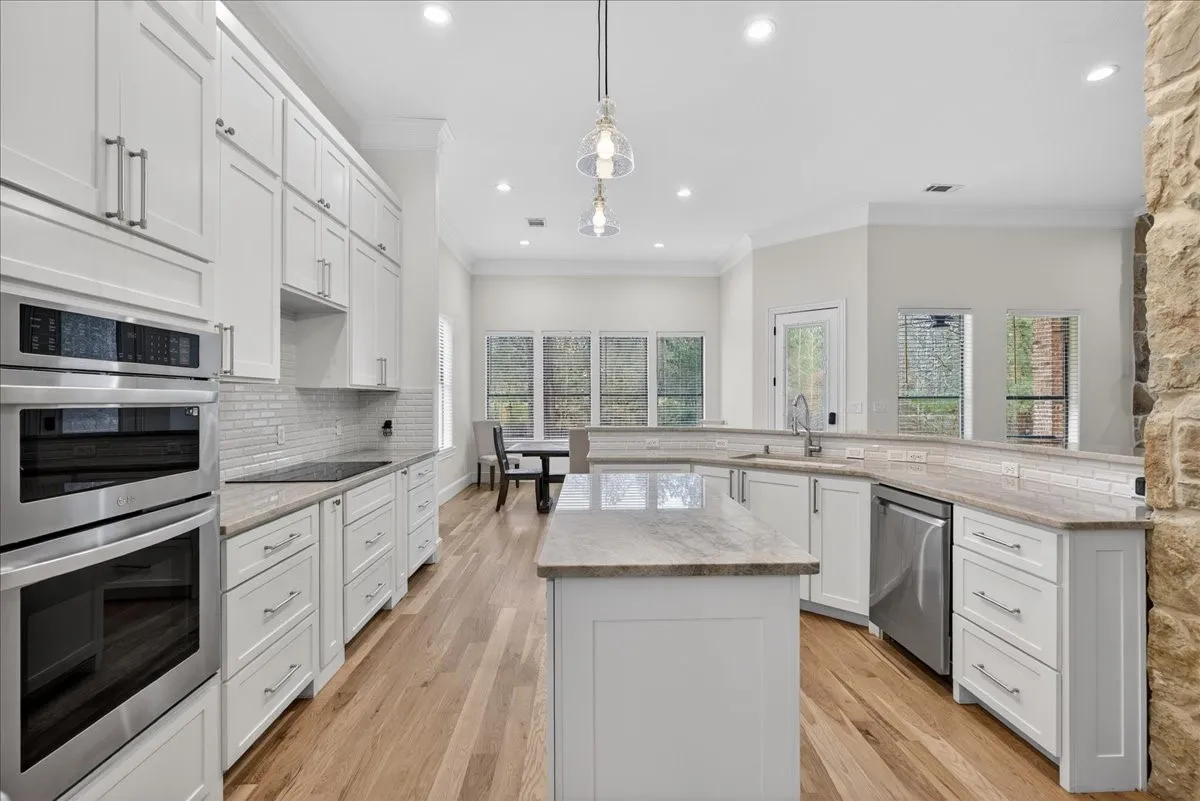 Kitchen featuring stainless steel appliances, white cabinets, pendant lighting, crown molding, and a kitchen island