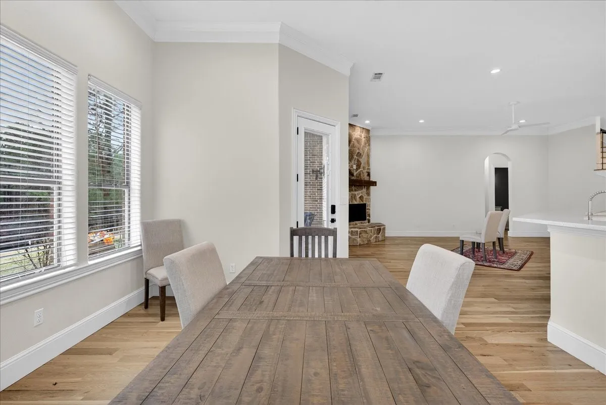 Dining space featuring arched walkways, crown molding, light wood-type flooring, a fireplace, and recessed lighting