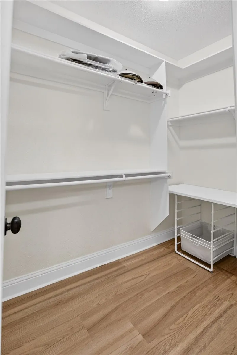 Walk in closet with light wood finished floors