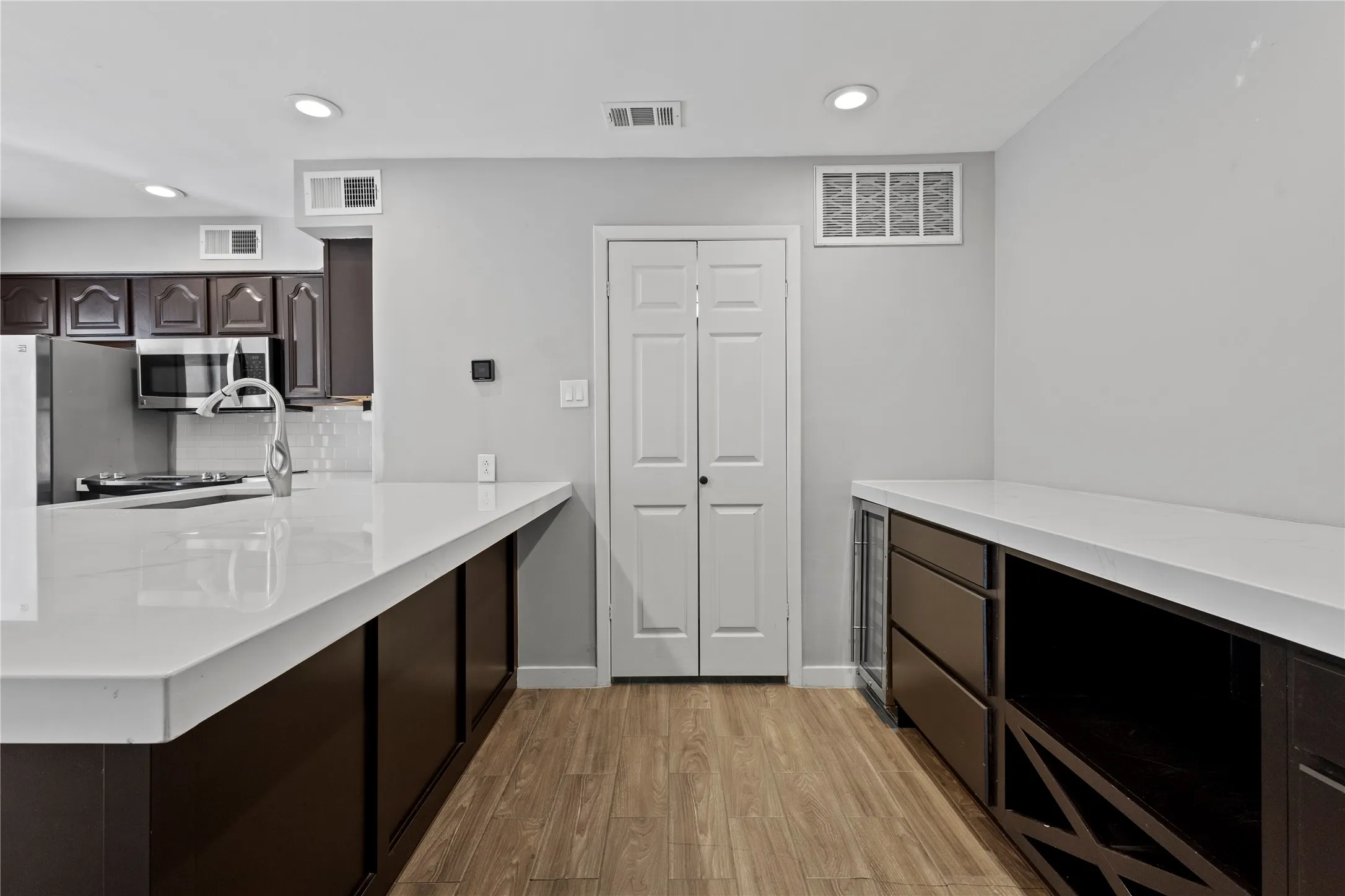 Kitchen featuring backsplash, dark brown cabinets, and light hardwood / wood-style floors