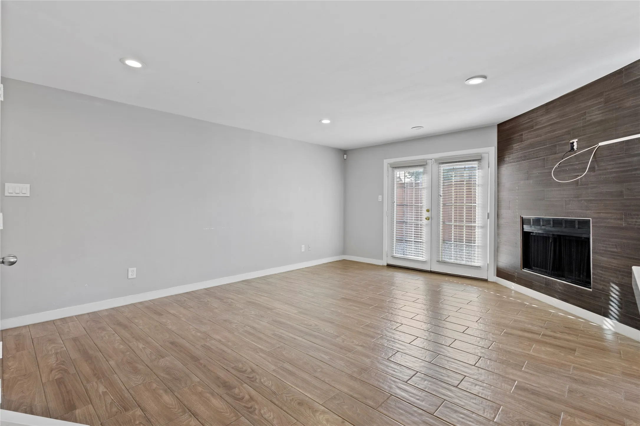 Unfurnished living room with a large fireplace, light hardwood / wood-style flooring, and french doors