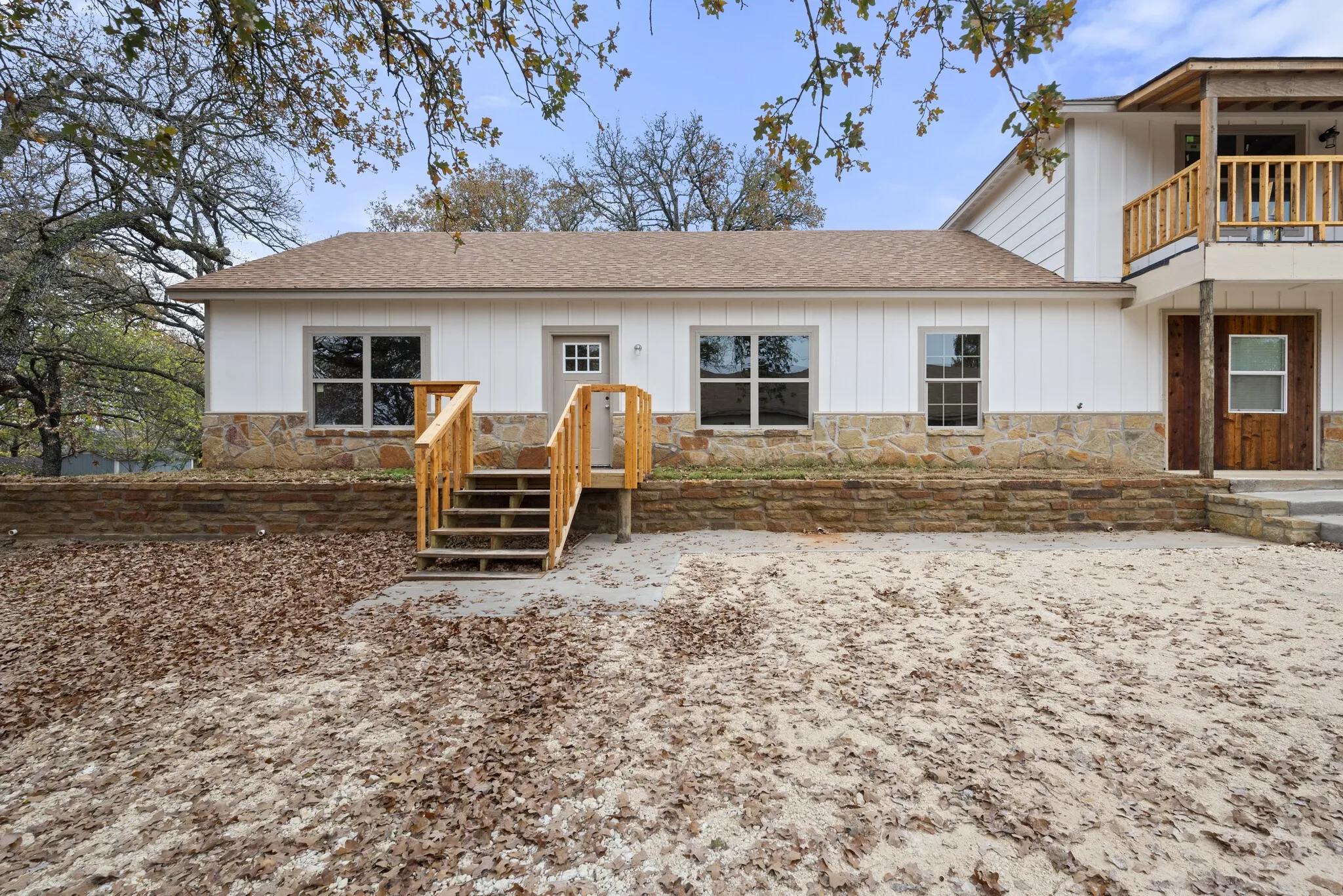 View of front of house featuring roof with shingles, stone siding, and board and batten siding