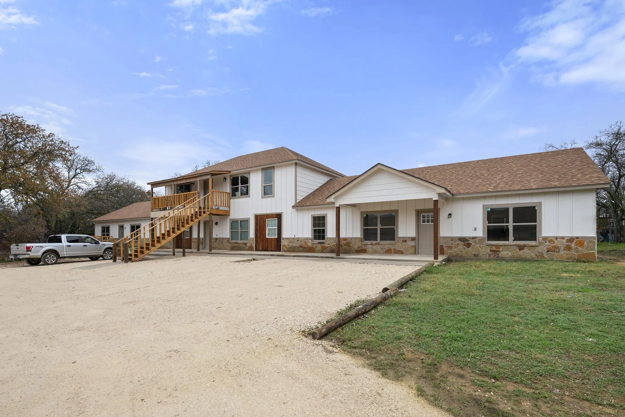 View of front of home featuring a shingled roof, board and batten siding, stone siding, and a front lawn