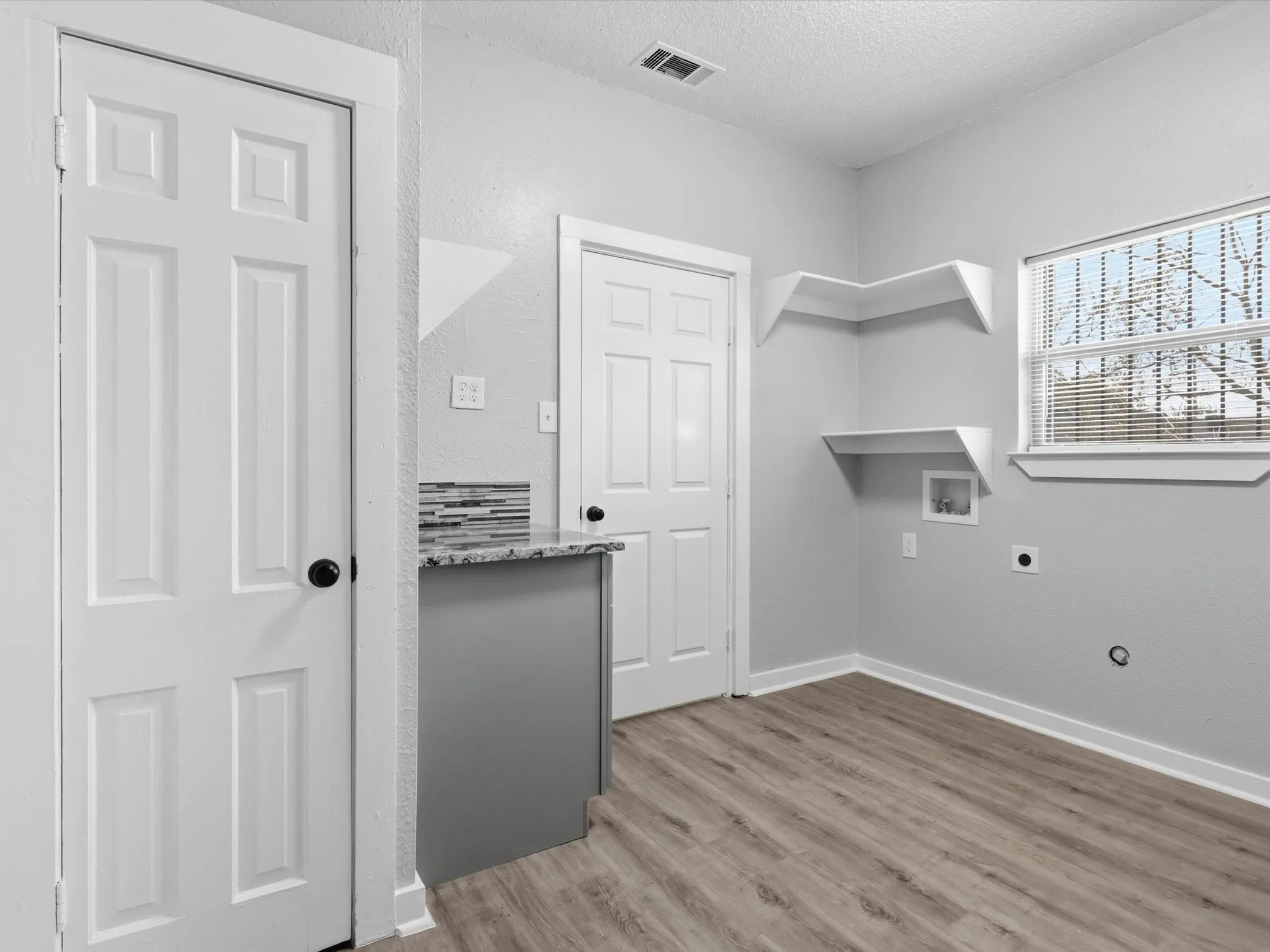Laundry area featuring a textured ceiling, light wood-style flooring, washer hookup, and hookup for an electric dryer