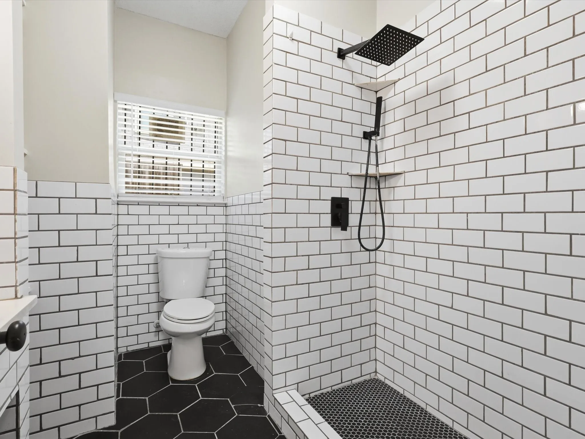Full bath with a stall shower, tile walls, a wainscoted wall, and dark tile patterned floors