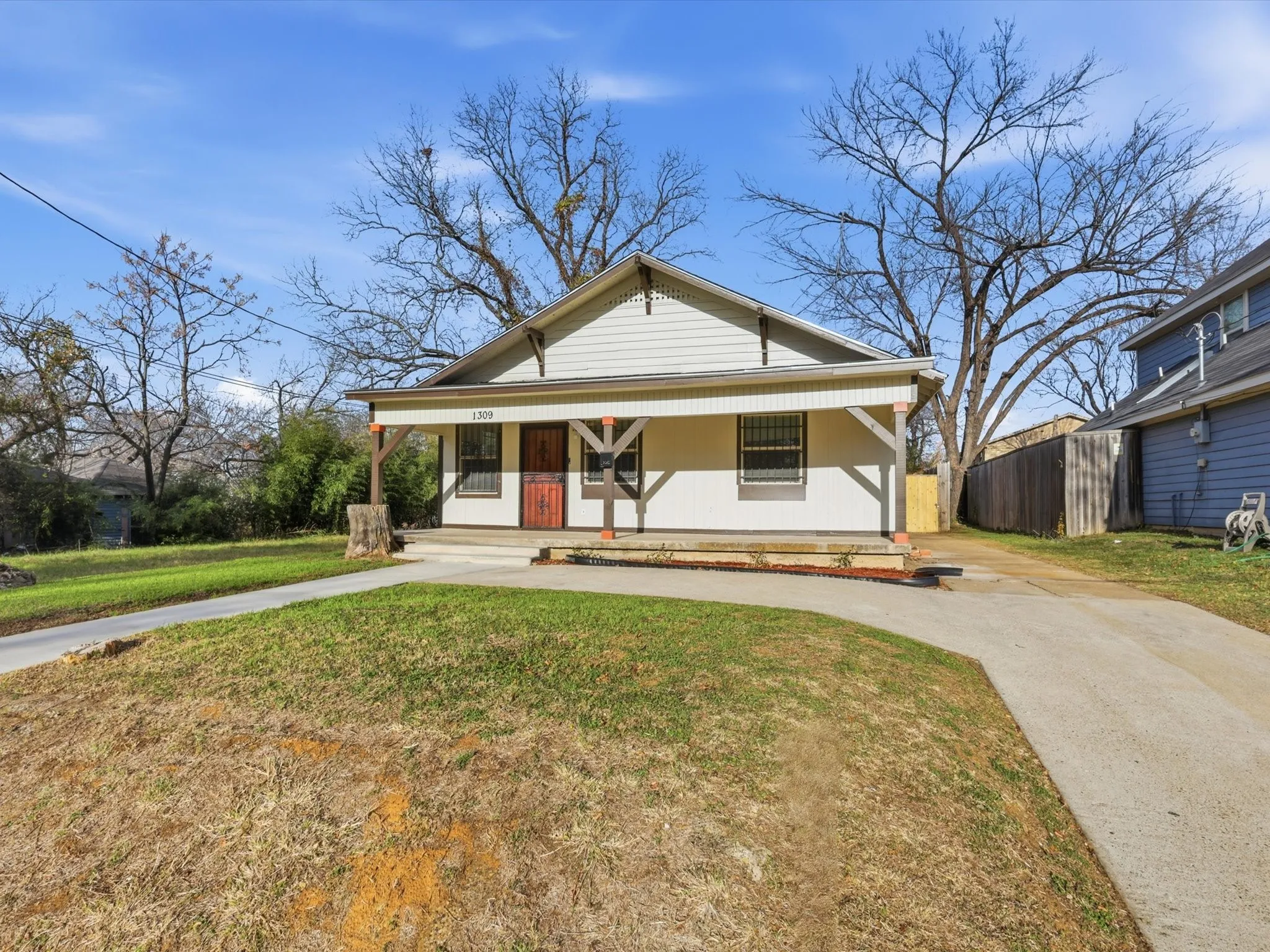 Bungalow featuring covered porch, a front lawn, and driveway