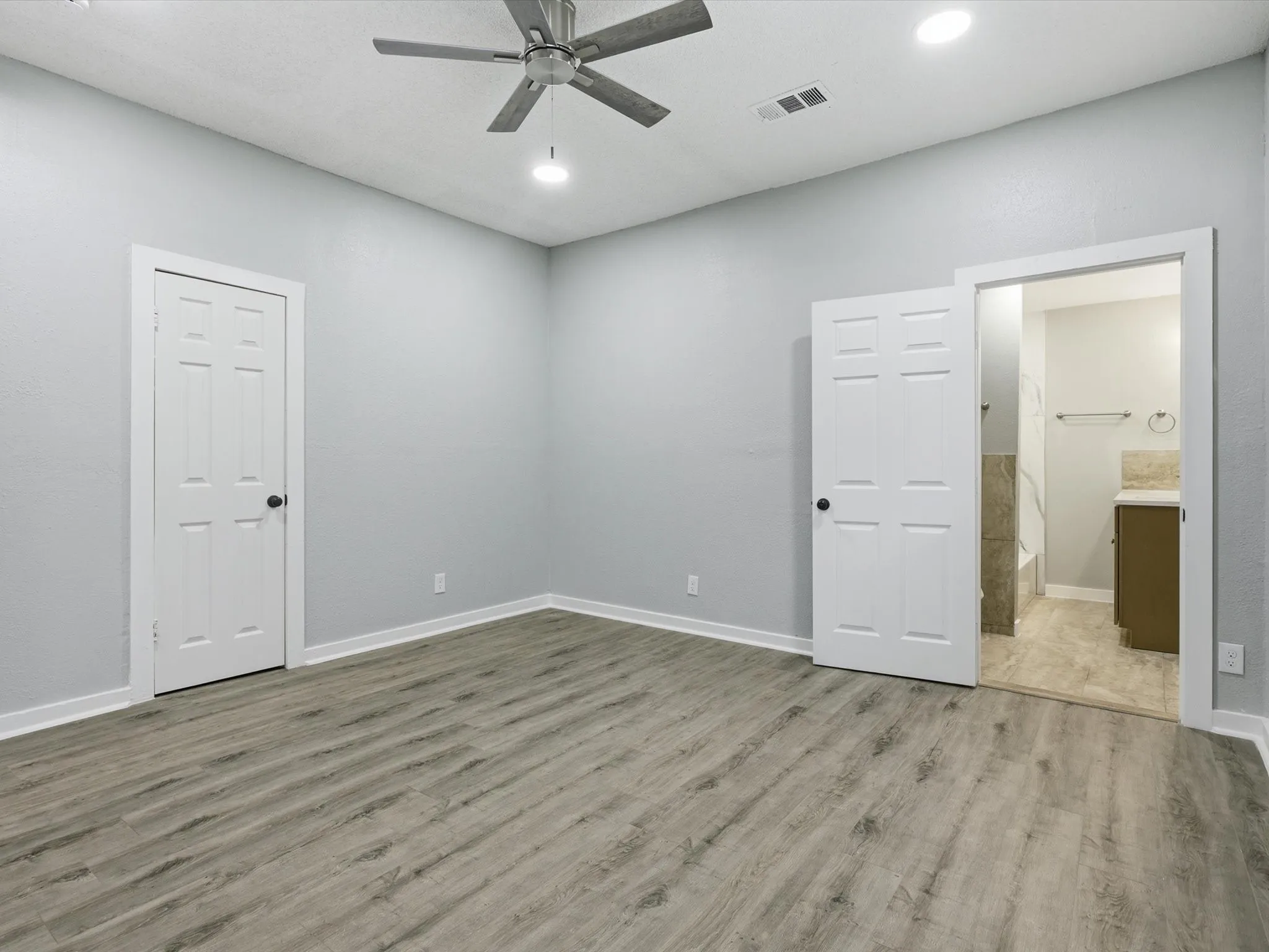 Unfurnished bedroom featuring a ceiling fan, light wood-style floors, ensuite bath, and recessed lighting