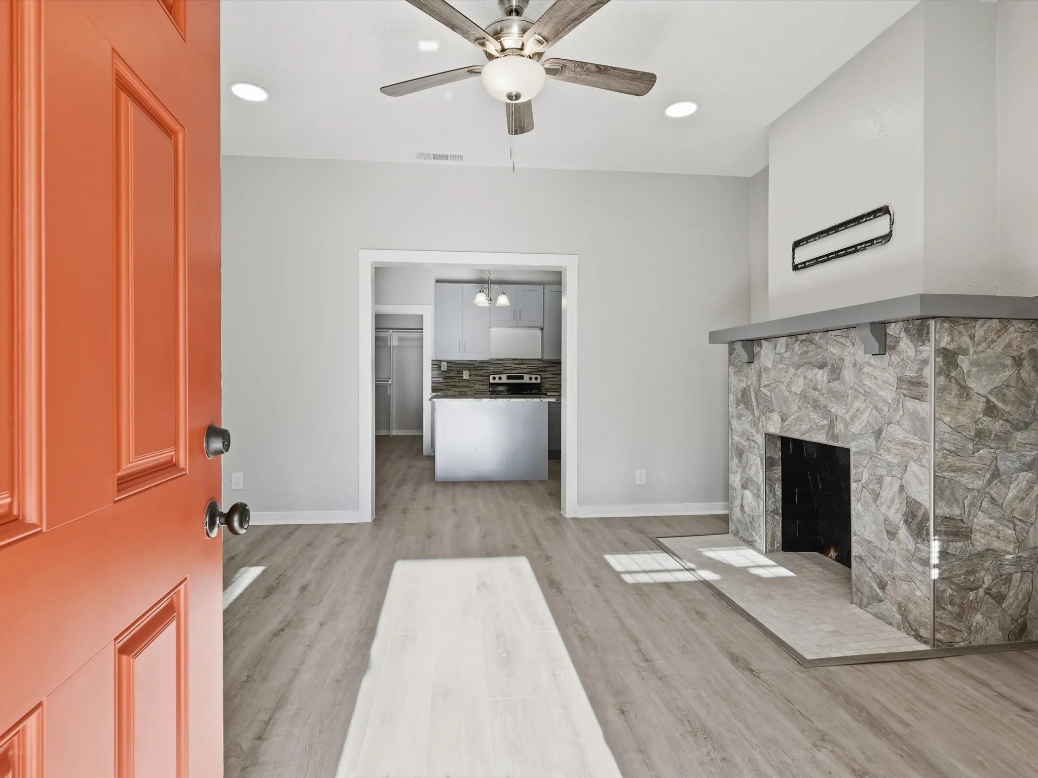 Unfurnished living room with light wood-type flooring, a ceiling fan, a fireplace, and recessed lighting