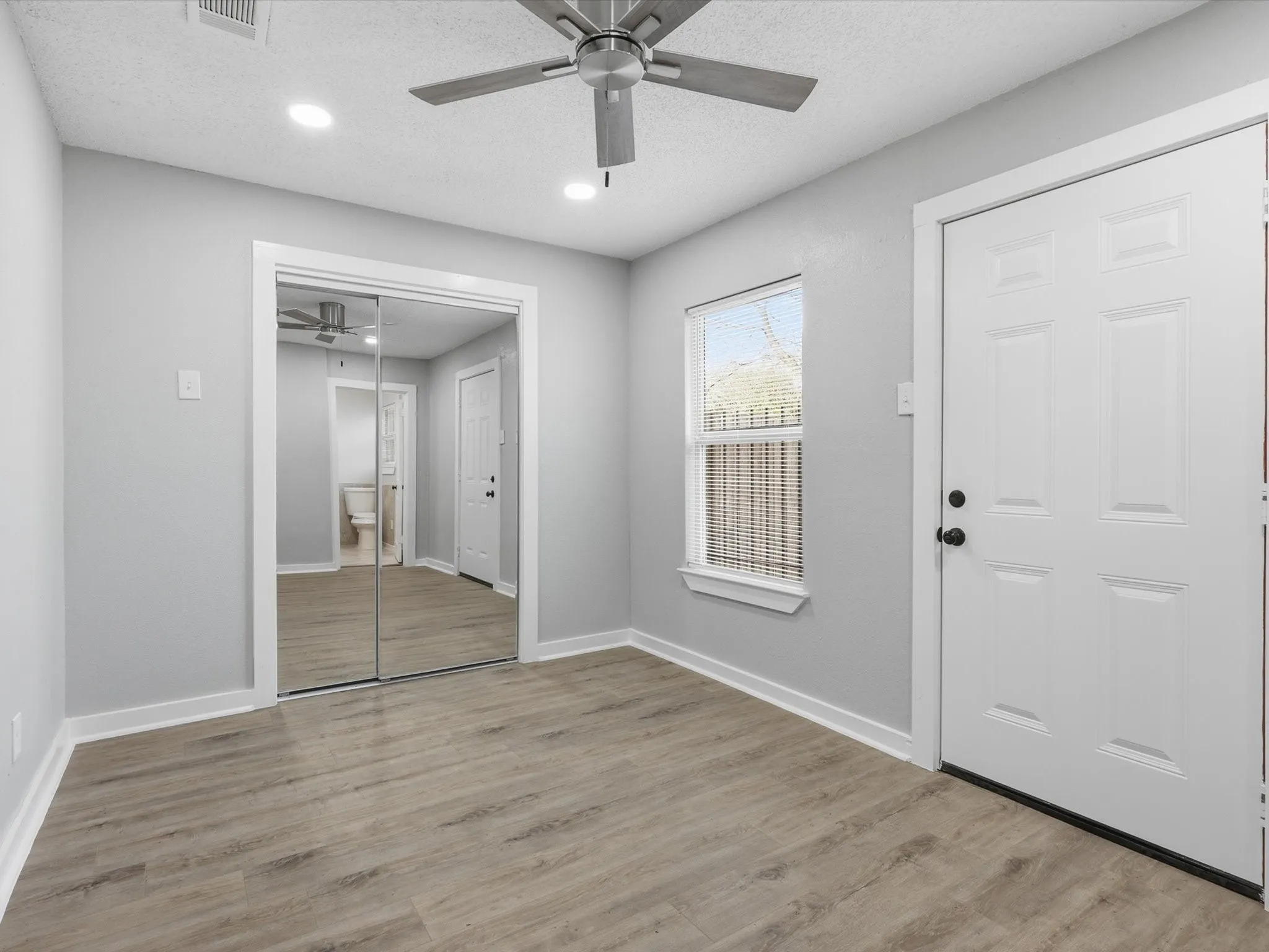 Foyer with a ceiling fan, a textured ceiling, light wood finished floors, and recessed lighting