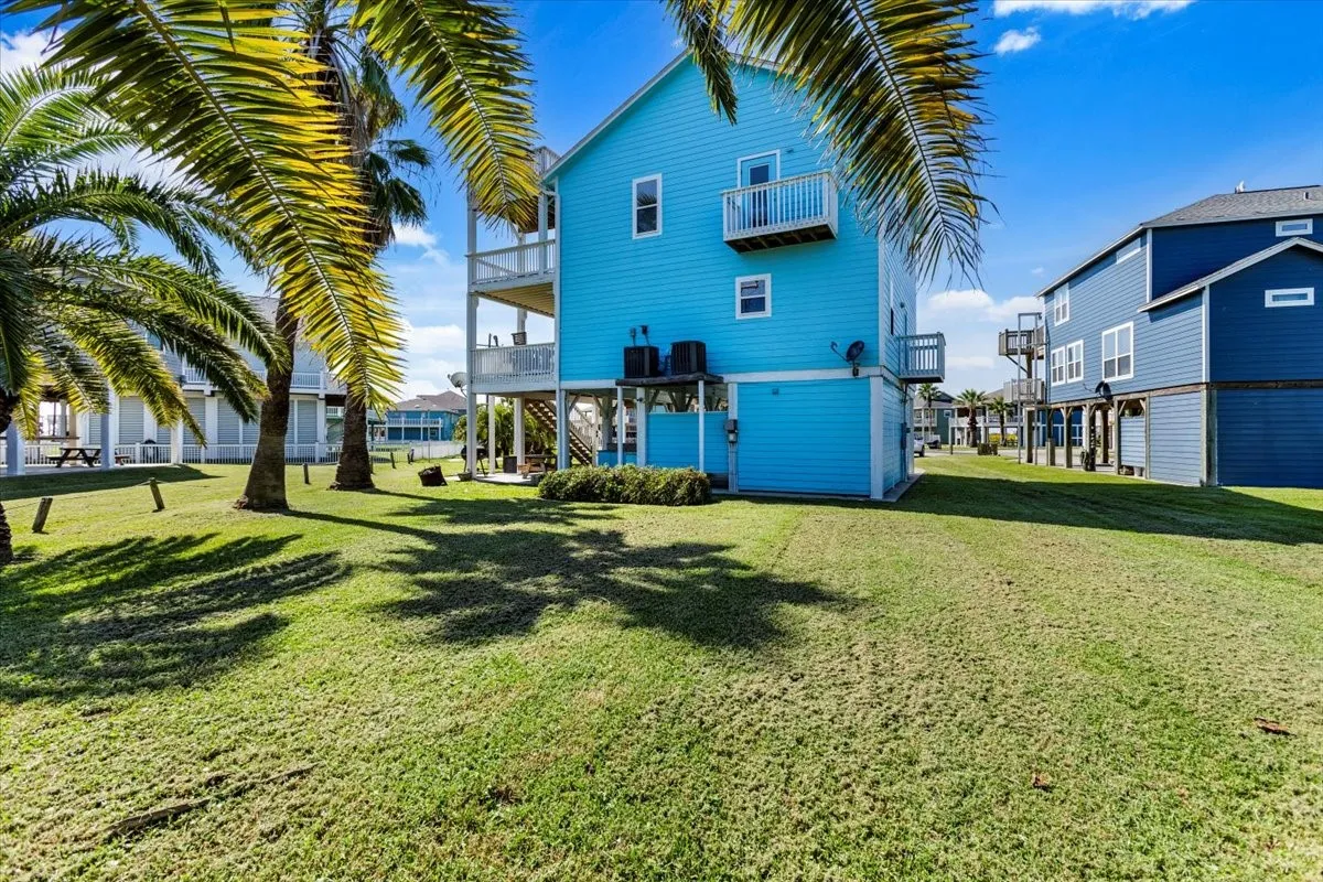 Back of house with a yard, central AC unit, and a balcony