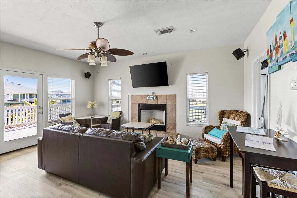 Living room with light hardwood / wood-style floors, a wealth of natural light, and a tile fireplace