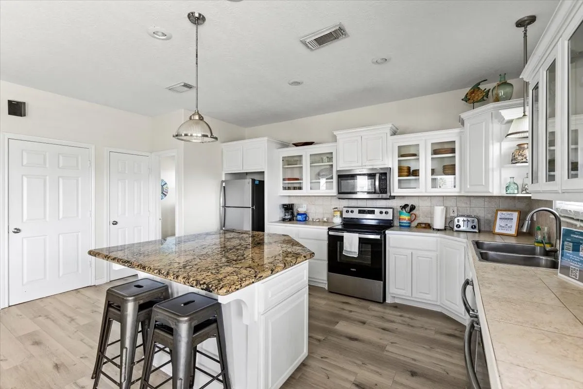 Kitchen featuring stainless steel appliances, a kitchen island, sink, and white cabinetry