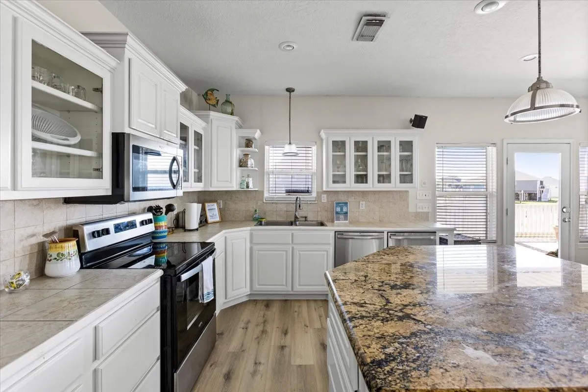 Kitchen featuring pendant lighting, sink, light hardwood / wood-style flooring, white cabinetry, and appliances with stainless steel finishes