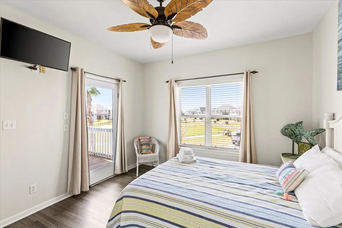 Bedroom featuring dark hardwood / wood-style floors, multiple windows, and ceiling fan