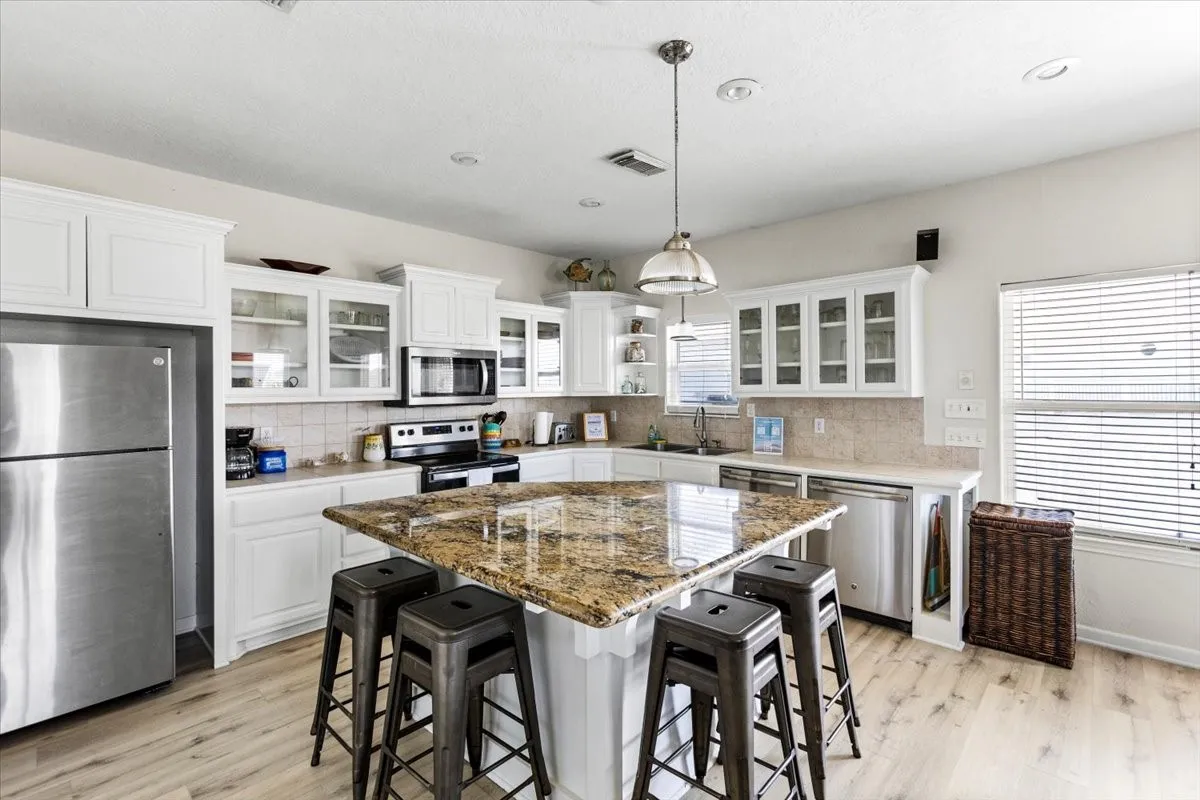 Kitchen with light hardwood / wood-style flooring, appliances with stainless steel finishes, a center island, and white cabinetry