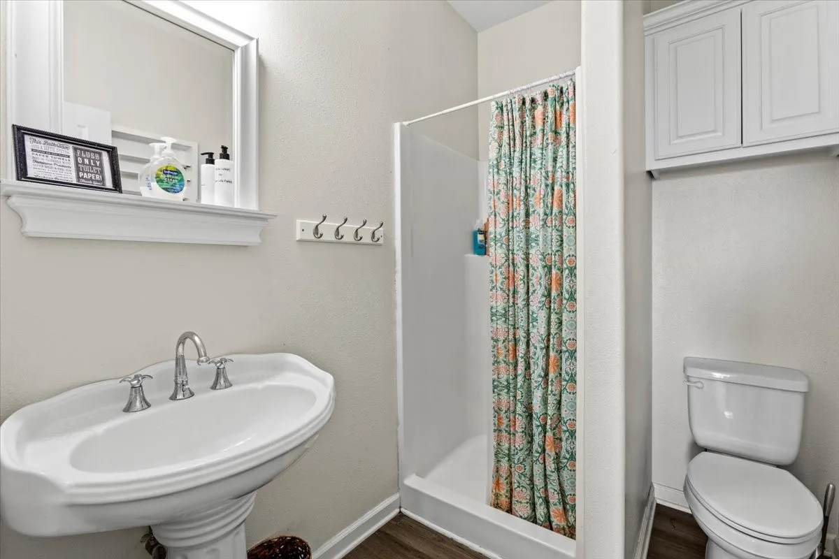 Bathroom featuring hardwood / wood-style flooring, sink, toilet, and a shower with shower curtain