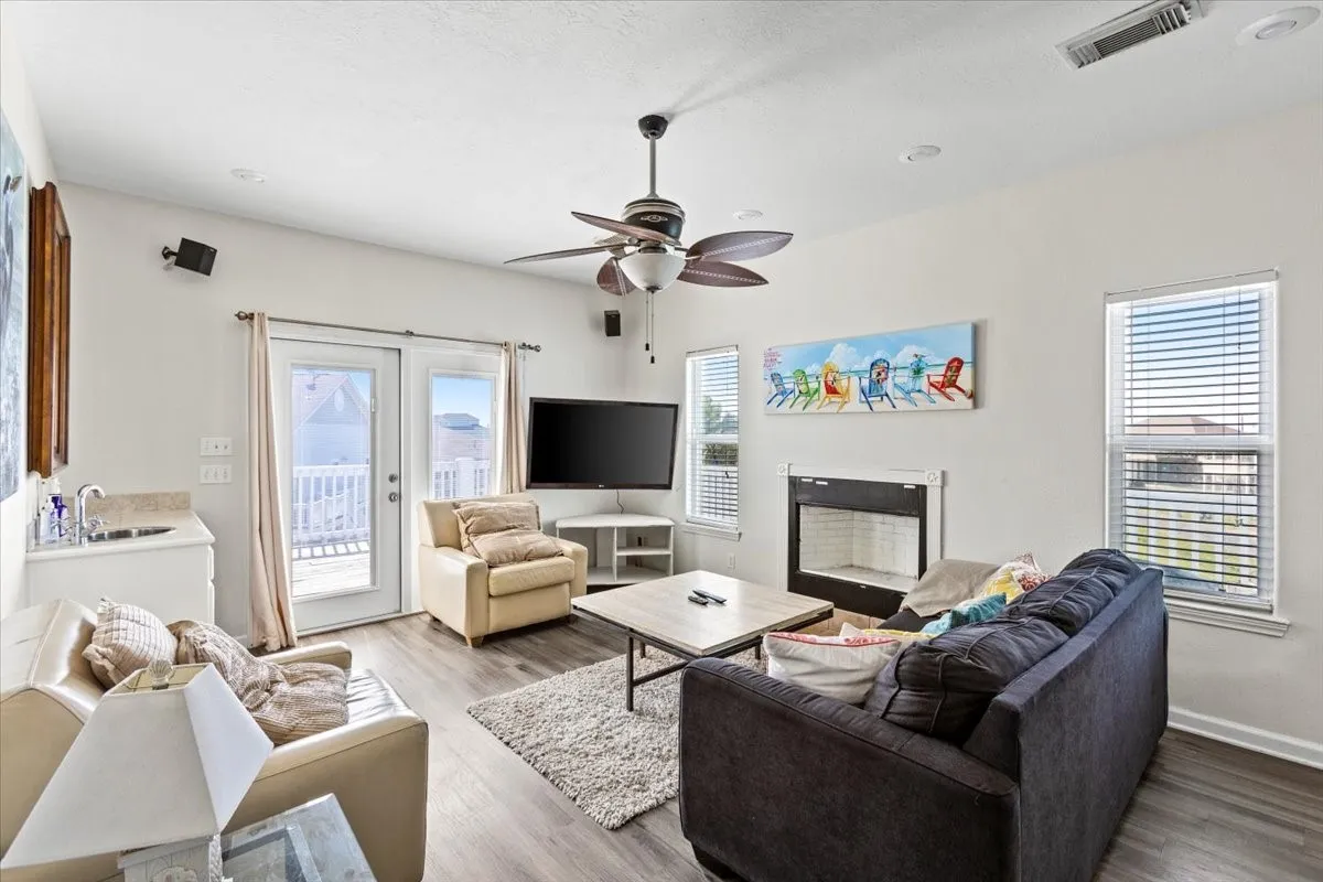 Living room with ceiling fan, a fireplace, plenty of natural light, and wood-type flooring