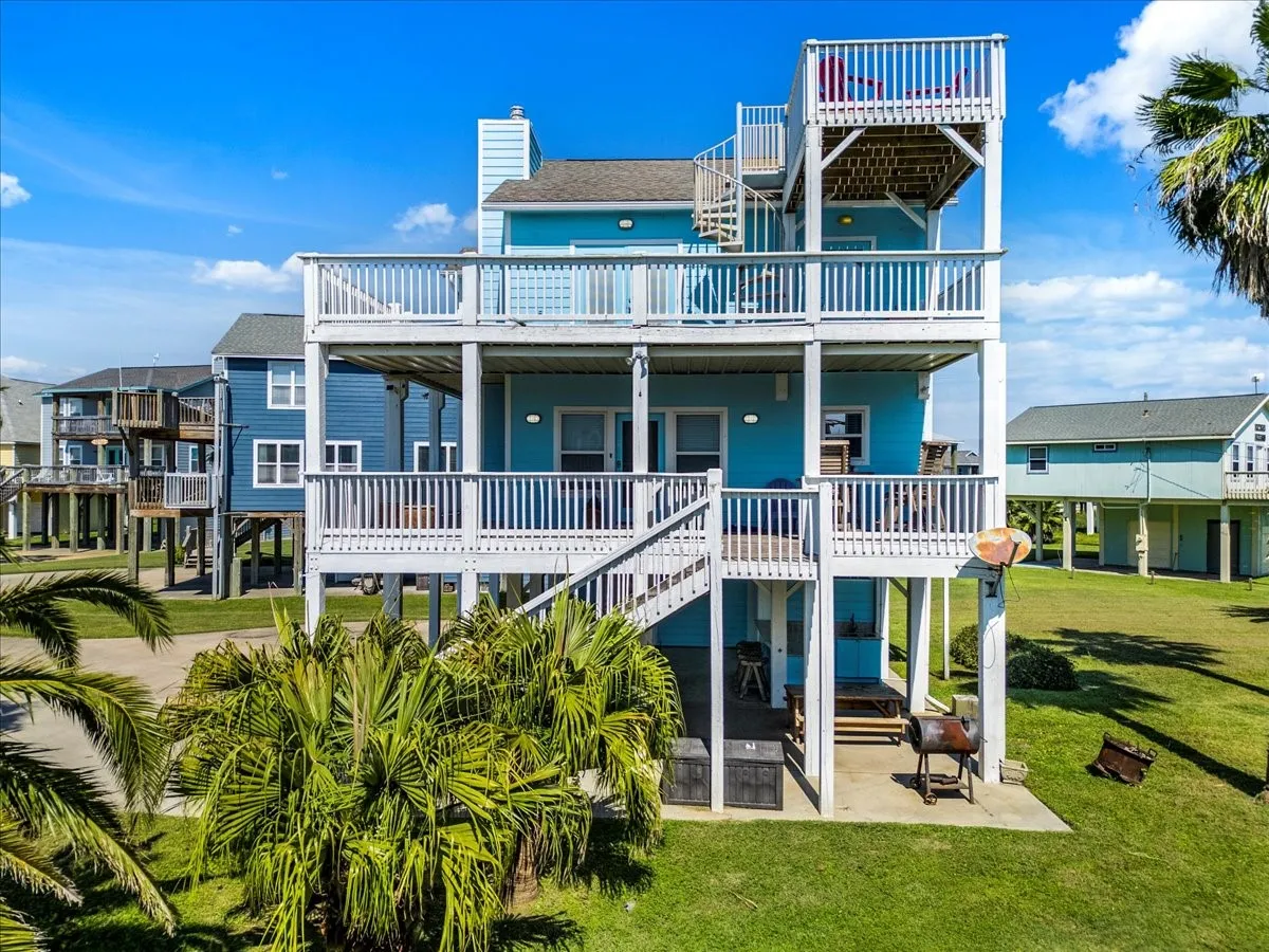 Rear view of house featuring a patio, a wooden deck, and a lawn