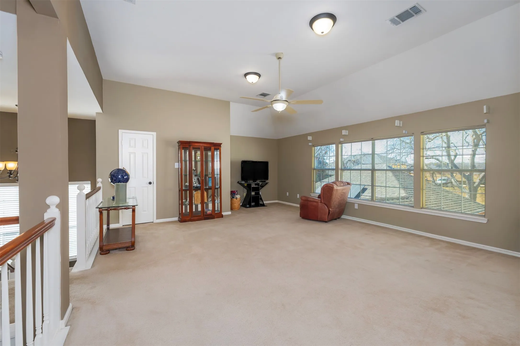 Sitting room with light colored carpet, a ceiling fan, vaulted ceiling, and hanging lights