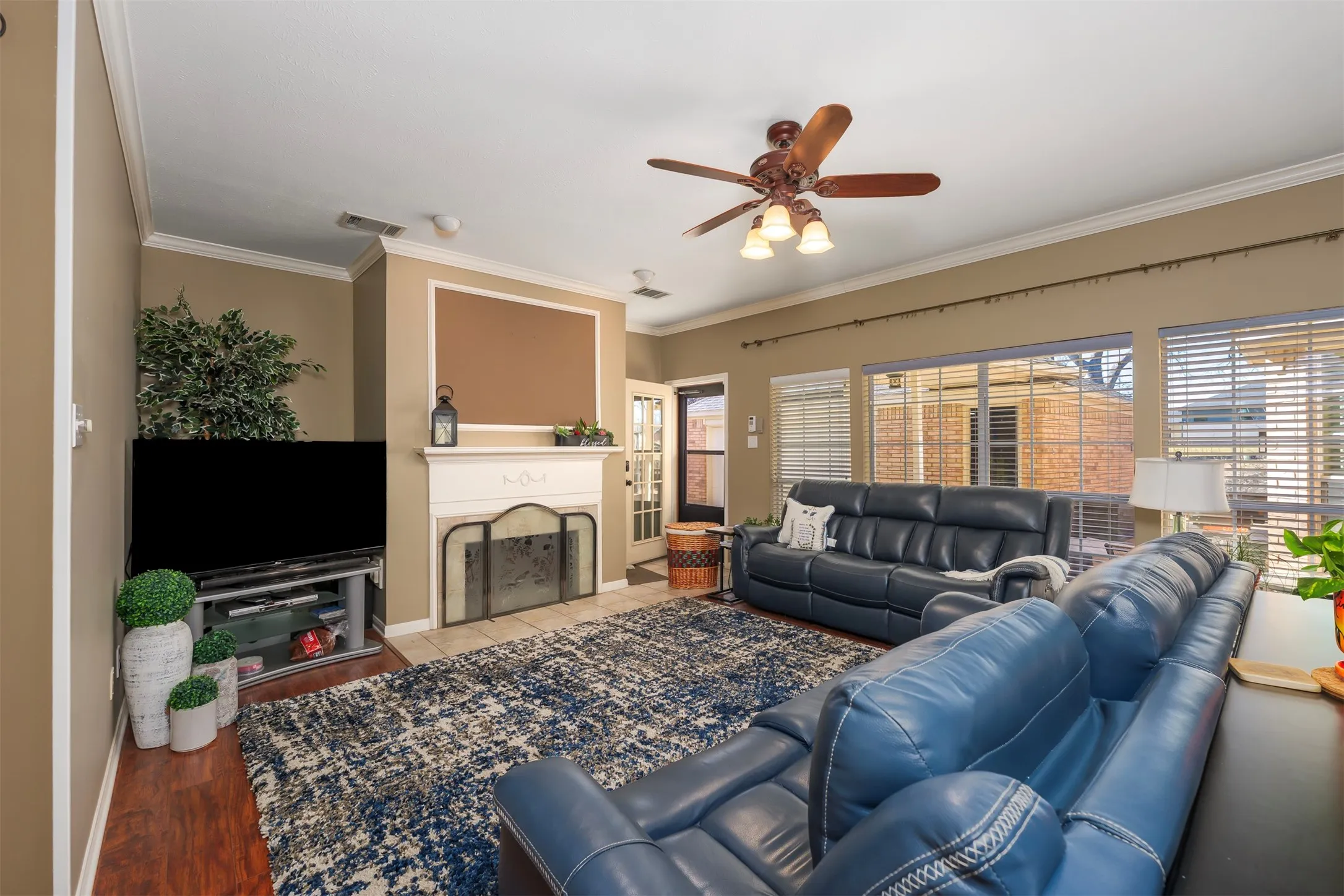 Living area with ceiling fan, a fireplace, and ornamental molding
