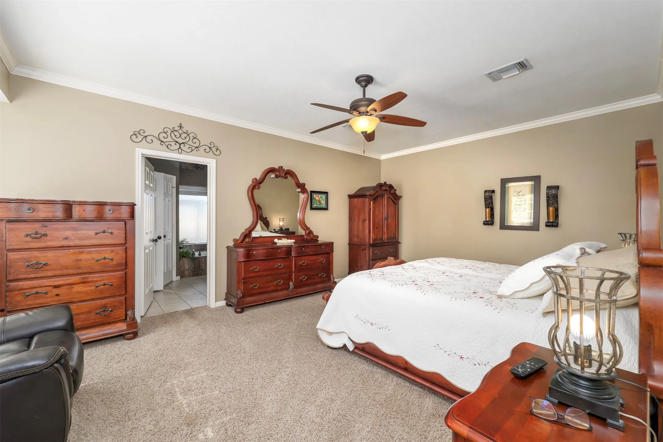 Bedroom with ornamental molding, carpet, a ceiling fan, and ensuite bath
