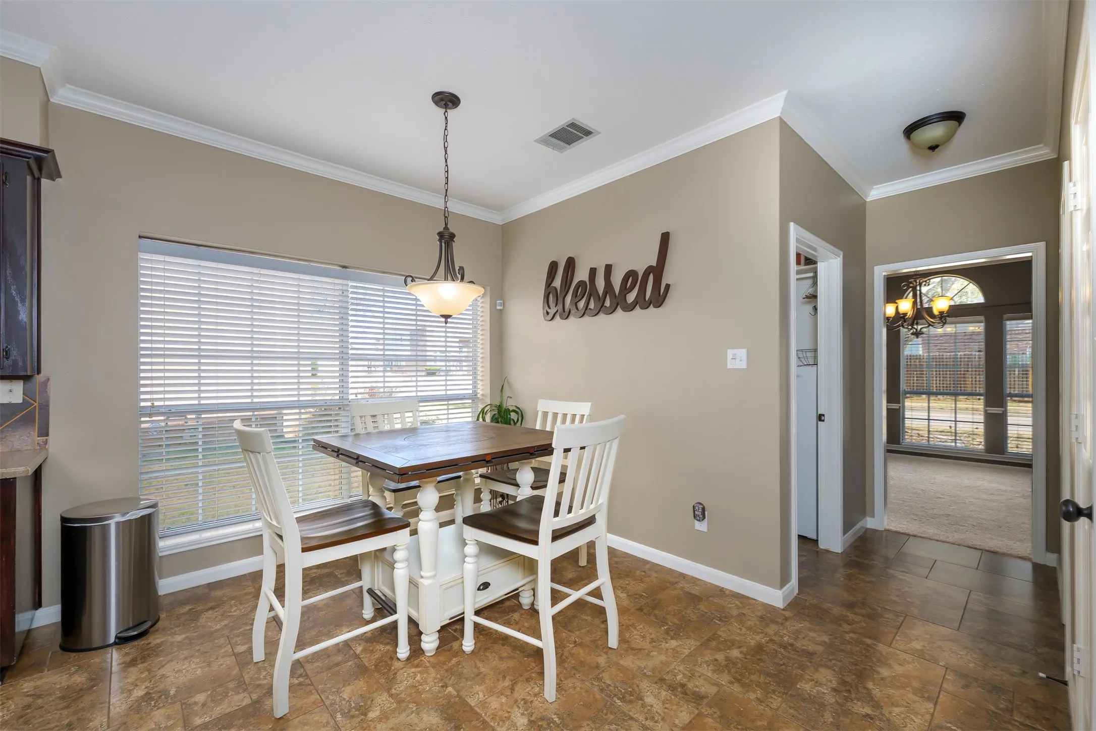 Dining room featuring stone finish floors, crown molding, a chandelier, and plenty of natural light