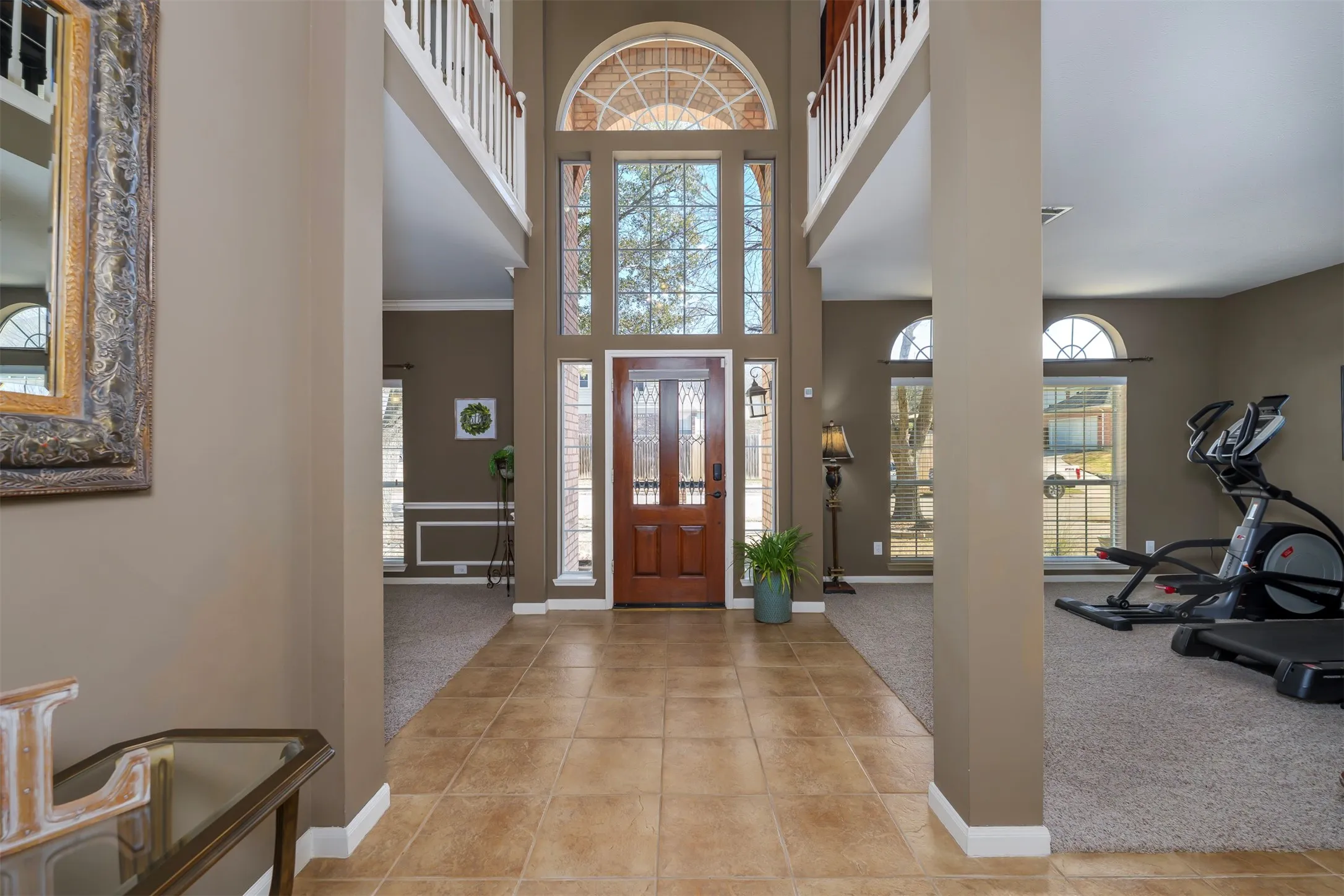 Entryway with light colored carpet, a high ceiling, ornamental molding, and light tile patterned floors