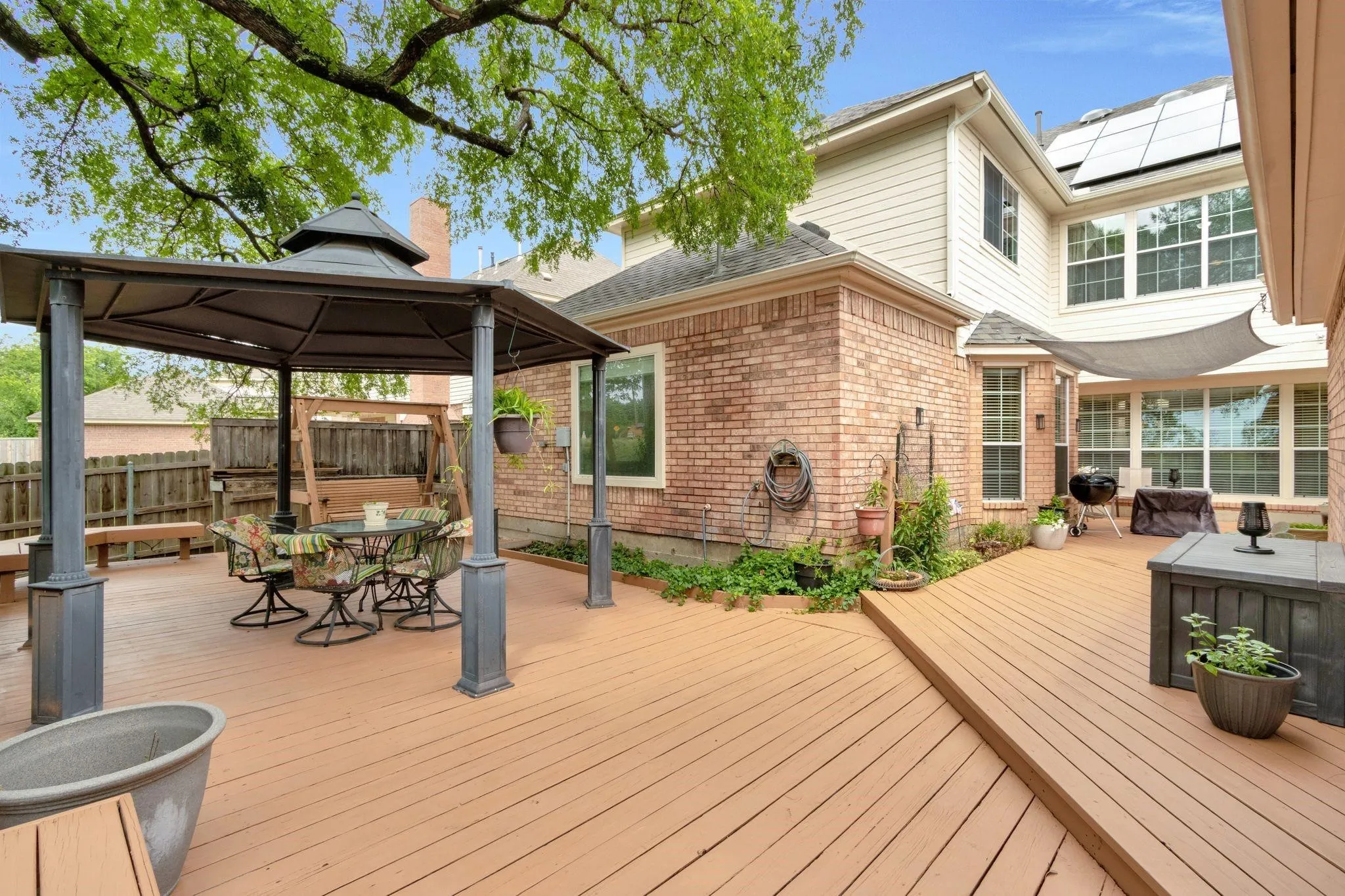 Wooden terrace with outdoor dining area, a gazebo, and a grill
