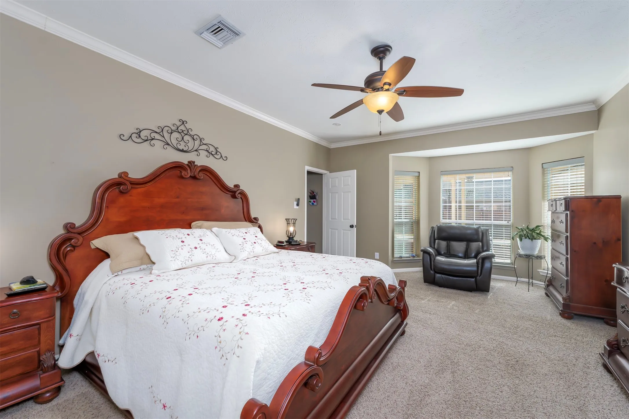 Carpeted bedroom with ornamental molding and ceiling fan