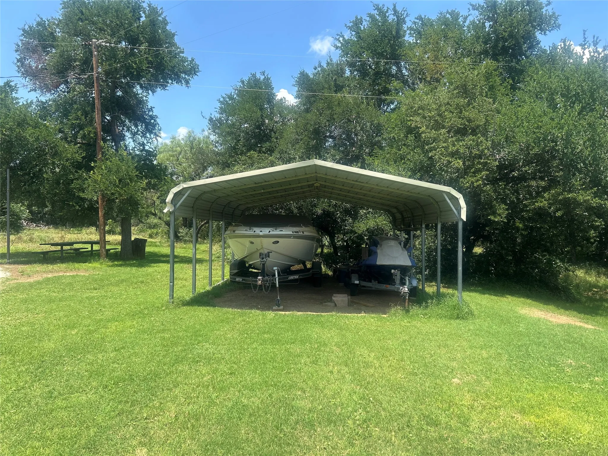 View of car parking featuring a carport and view of wooded area