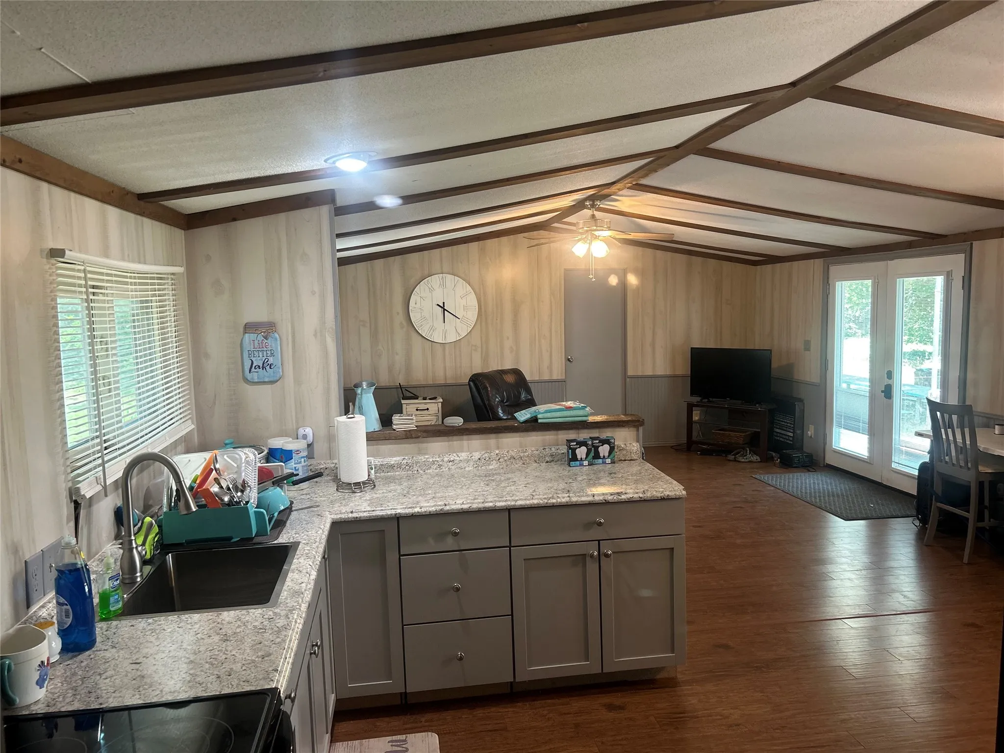 Kitchen with gray cabinets, open floor plan, wood walls, a peninsula, and dark wood finished floors