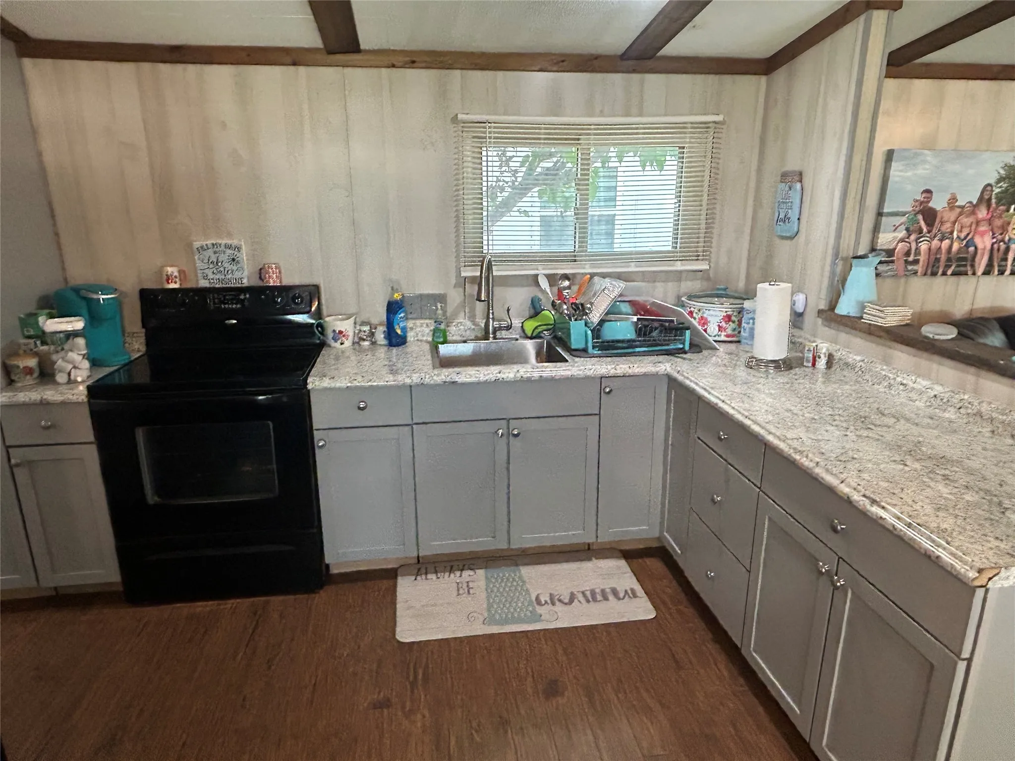 Kitchen featuring electric range, gray cabinets, beam ceiling, dark wood-style floors, and wood walls